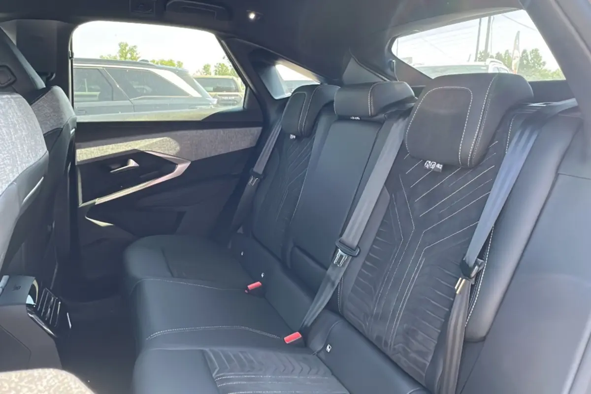 Vue intérieure arrière du Peugeot 3008 Hybrid 145 GT Alcantara avec sellerie cuir noir et inserts tissu gris.