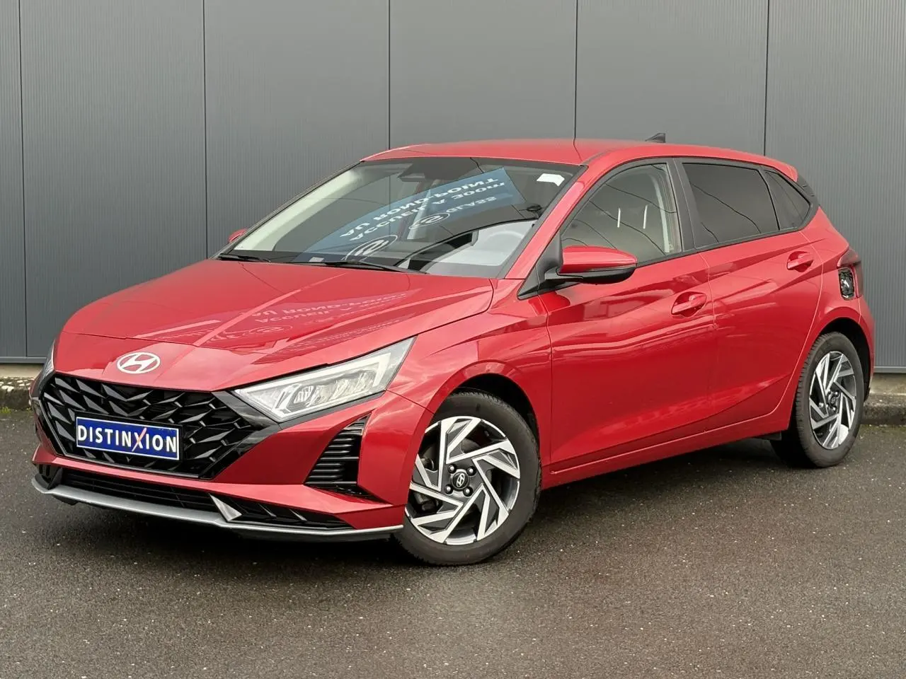 Vue 3/4 avant d'une Hyundai i20 2025 rouge Dragon Metal avec jantes alliage et calandre noire distinctive.
