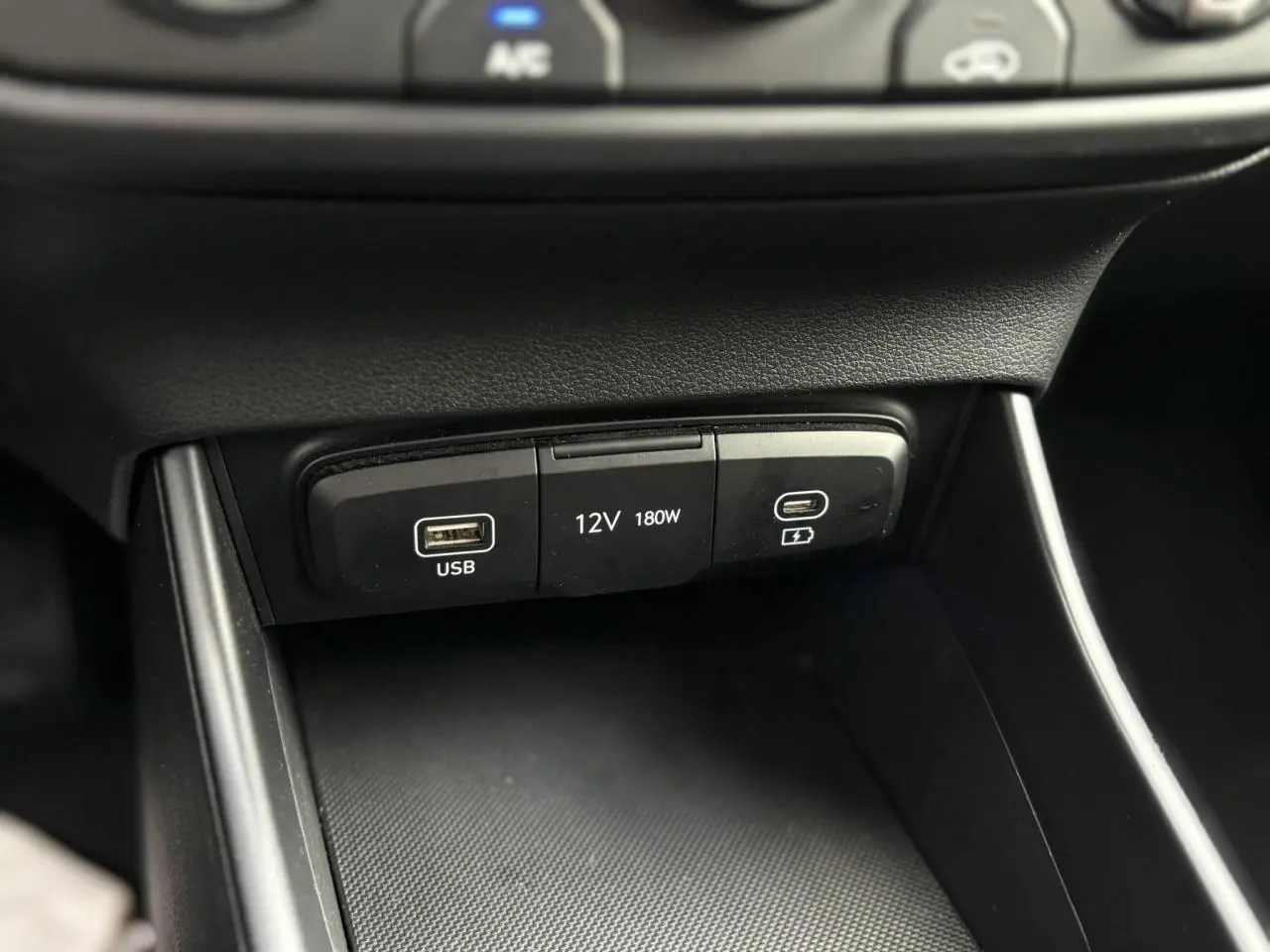 Gros plan sur la console centrale de la Hyundai i20 2025, montrant les ports USB et prise 12V noirs.