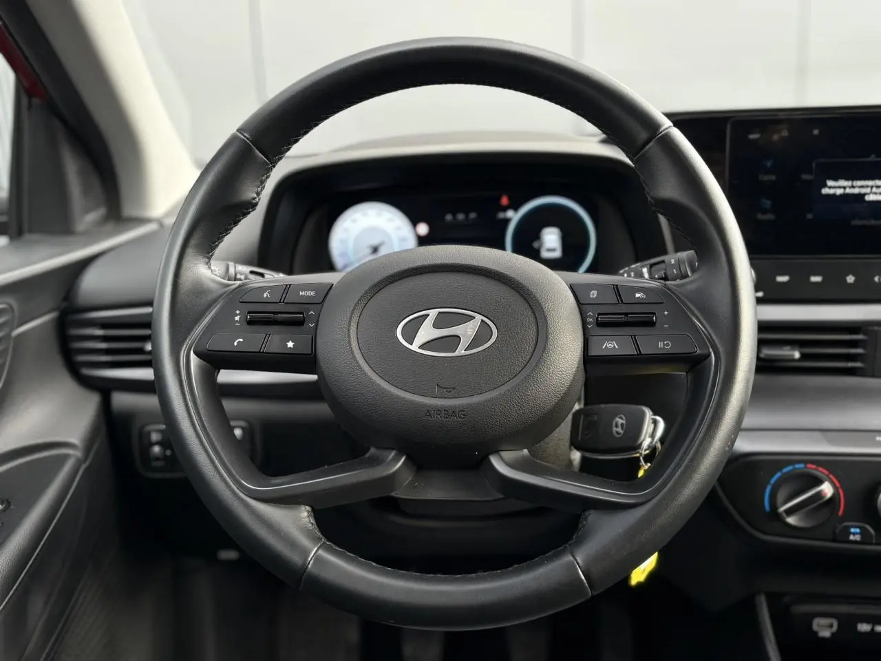 Vue rapprochée du volant cuir multifonction de la Hyundai i20 2025 avec tableau de bord numérique et commandes intégrées.