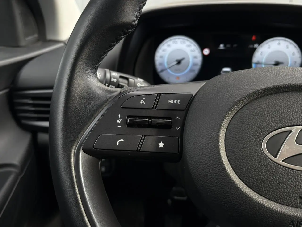Gros plan sur le volant multifonction noir de la Hyundai i20 2025 avec commandes audio et téléphone intégrées.
