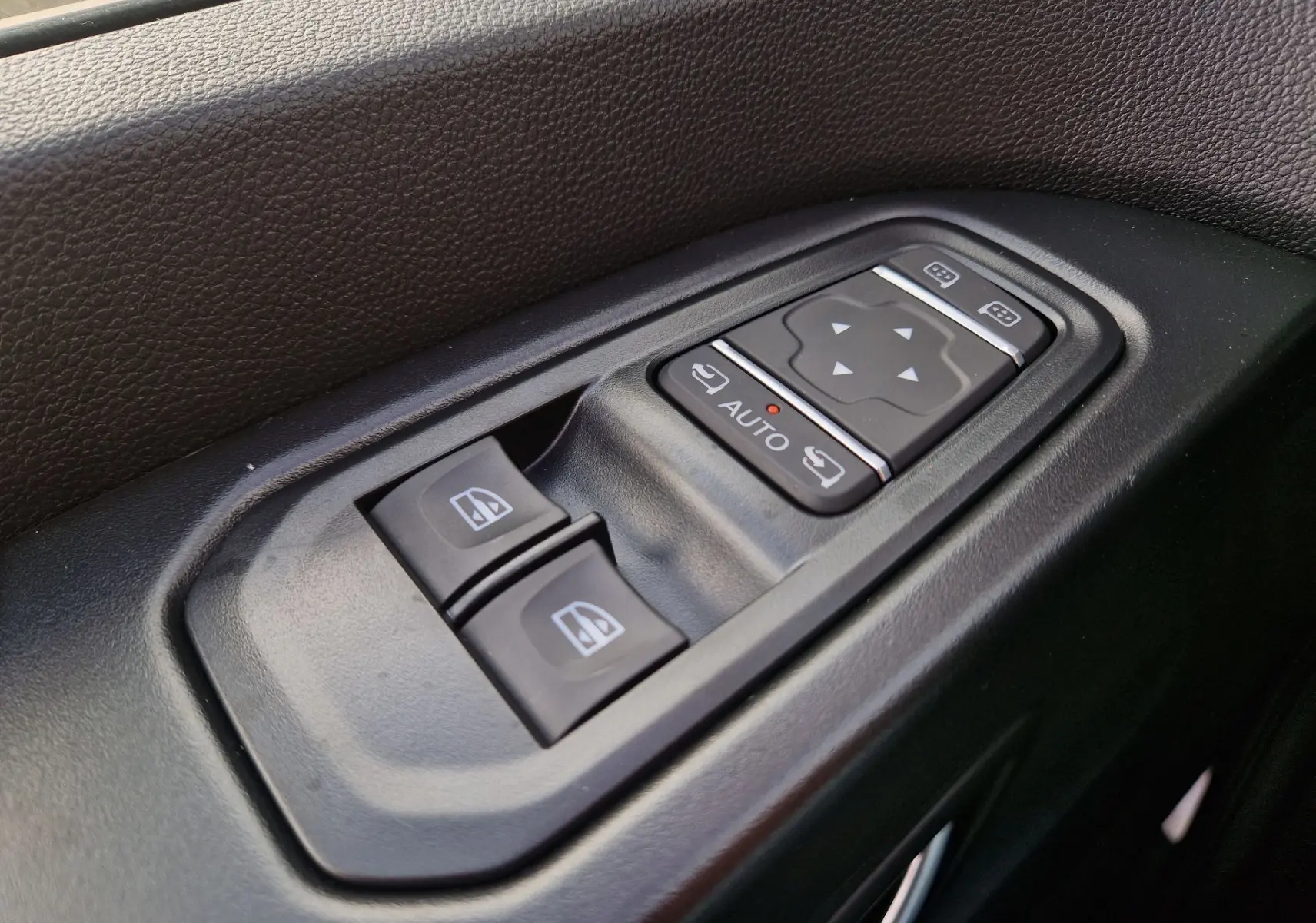 Gros plan sur les commandes de lève-vitres et réglage des rétroviseurs côté conducteur du Nissan Primastar 2025.