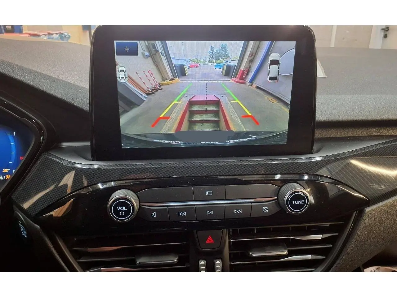 Vue intérieure du tableau de bord du Ford Kuga 2024 avec écran tactile affichant la caméra de recul en marche.