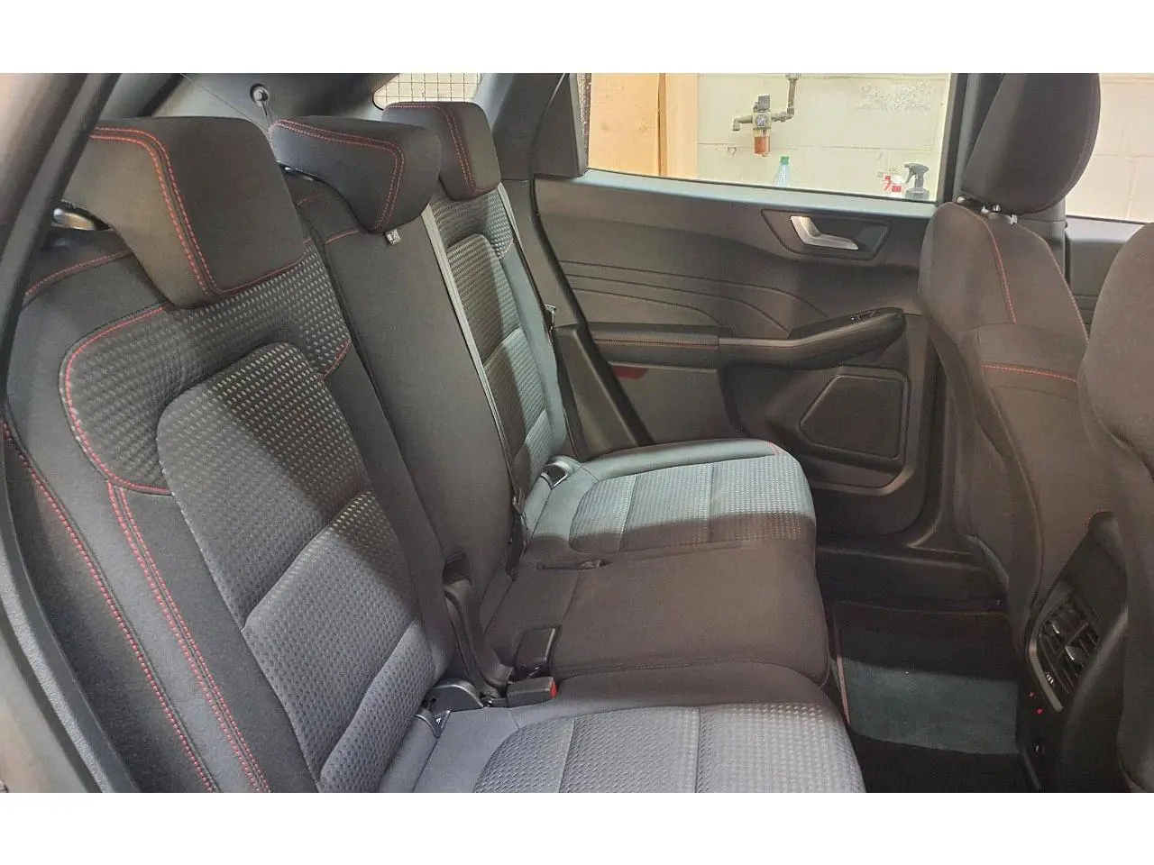 Vue intérieure côté droit des sièges arrière noirs avec surpiqûres rouges du Ford Kuga 2.0 EcoBlue 120 BVA ST-Line 2024.