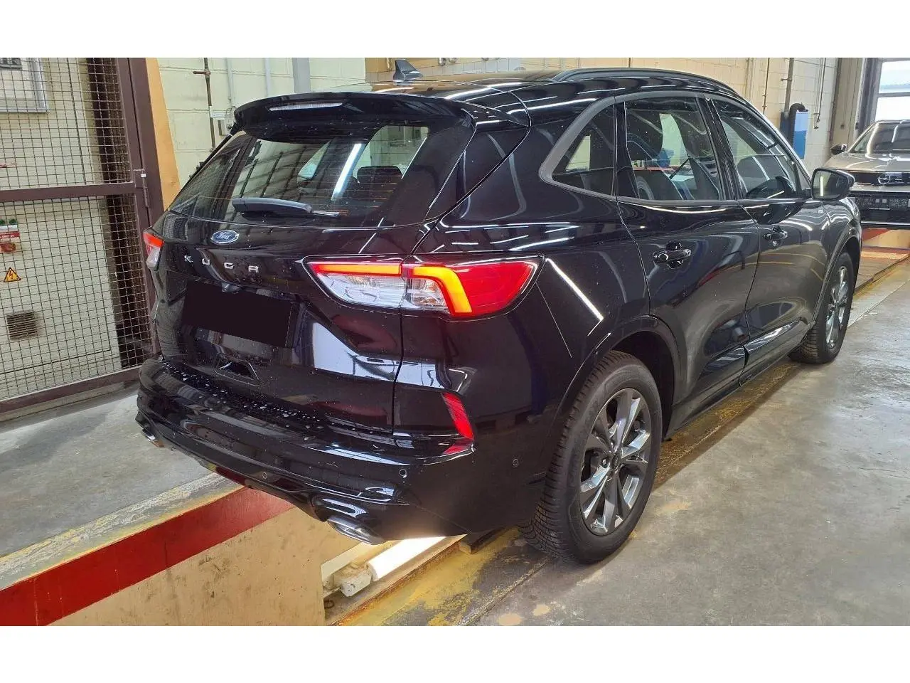 Vue 3/4 arrière droite du Ford Kuga 2024 noir Agathe avec feux LED et double sortie d’échappement ST-Line visible.