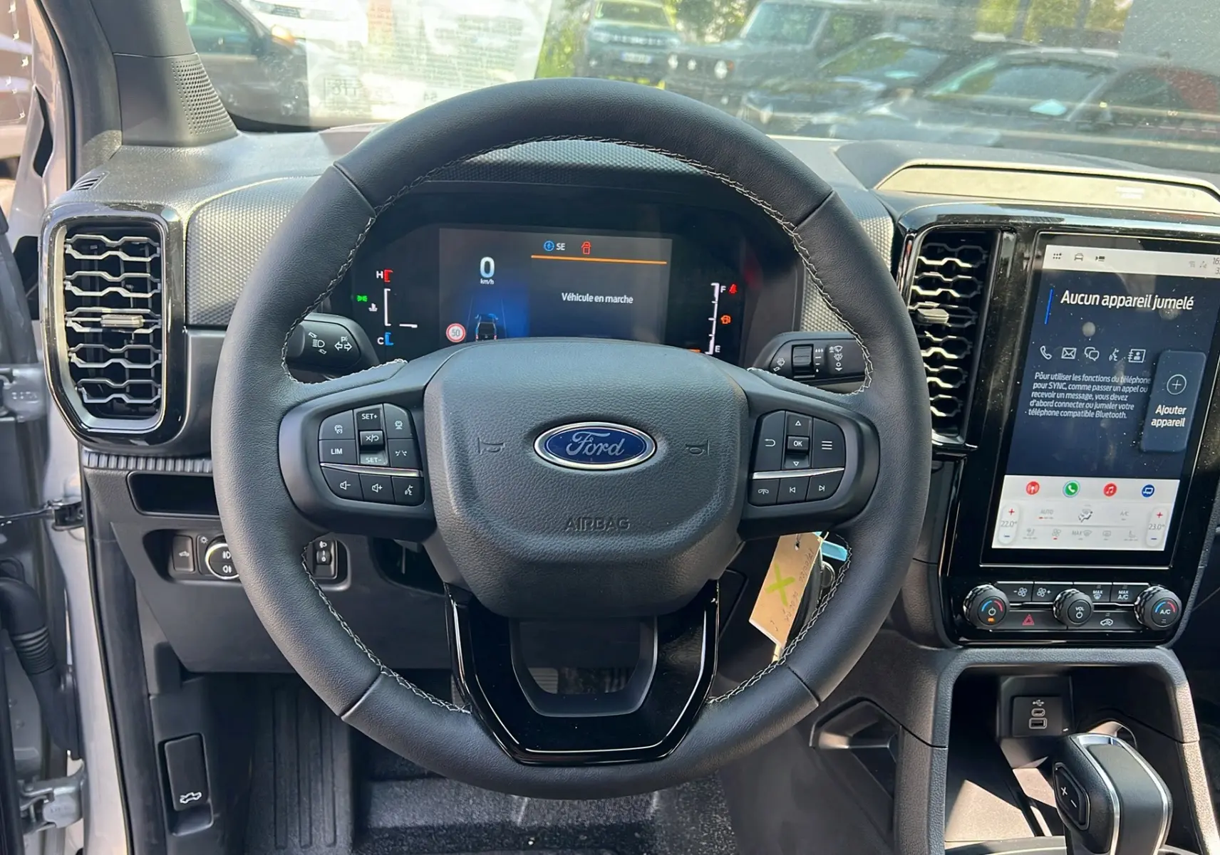 Vue intérieure centrée sur le volant cuir multifonctions du Ford Ranger 2025 avec écran tactile et tableau de bord numérique.