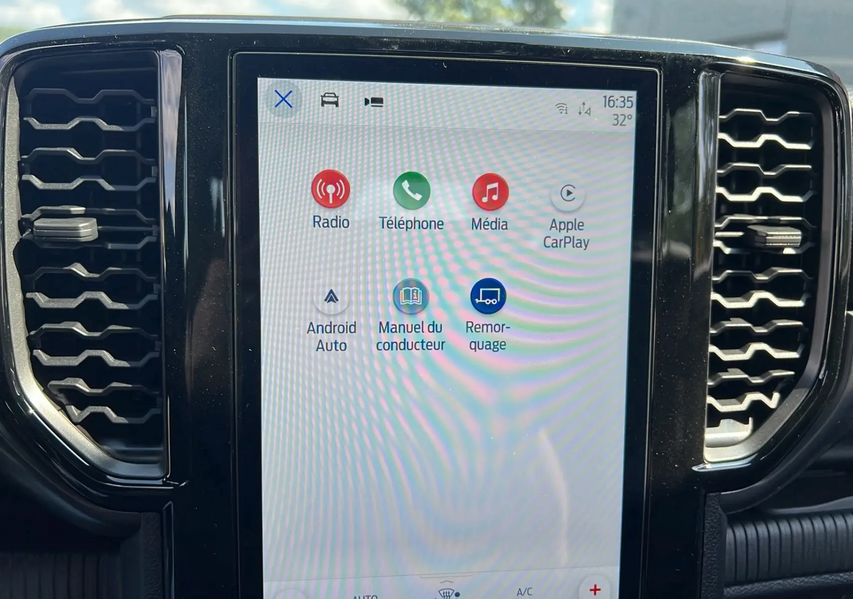 Écran tactile central du Ford Ranger 2025 affichant les options Radio, Téléphone, Média et Apple CarPlay, entouré de grilles d’aération noires.