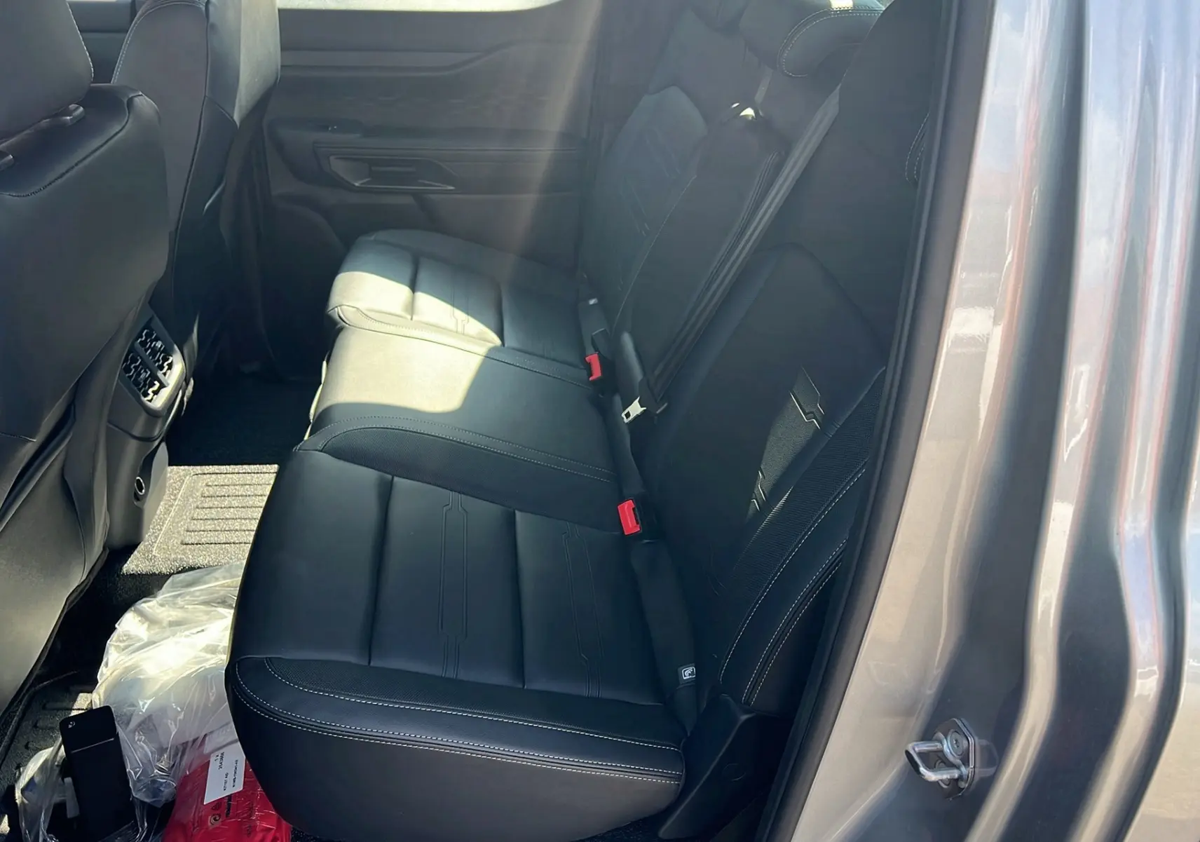 Vue intérieure arrière droite du Ford Ranger 2025 gris iconic, montrant les sièges en cuir noir avec surpiqûres blanches.