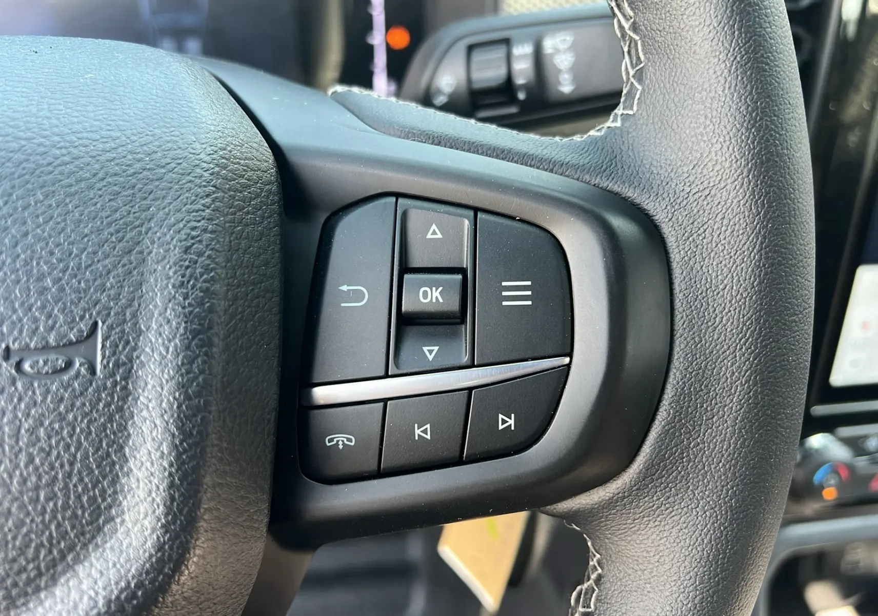Gros plan sur les commandes multifonctions à droite du volant cuir du Ford Ranger 2025, intérieur noir.