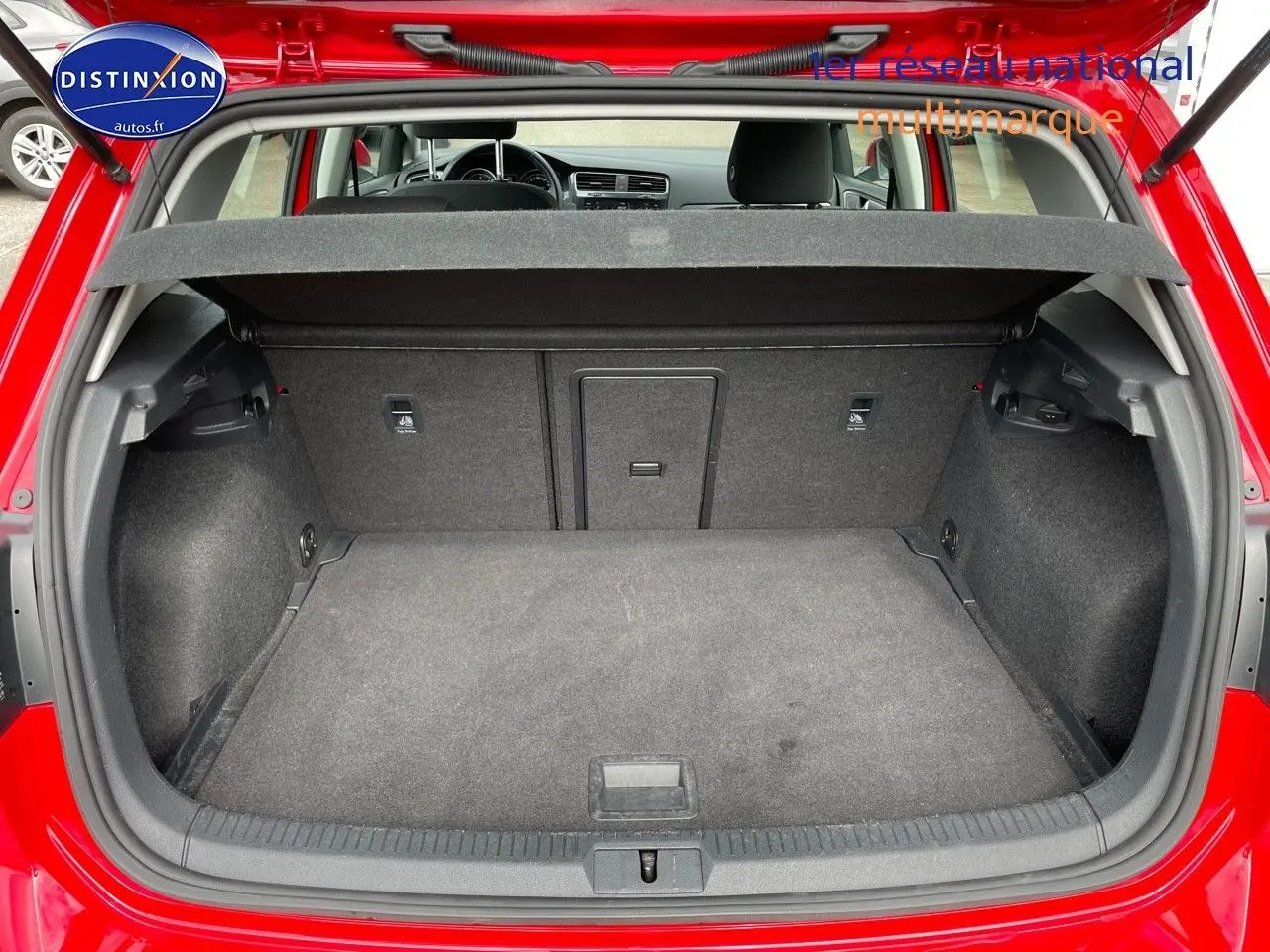 Coffre ouvert d'une Volkswagen Golf rouge vue de l'arrière, montrant un espace de chargement propre et spacieux.
