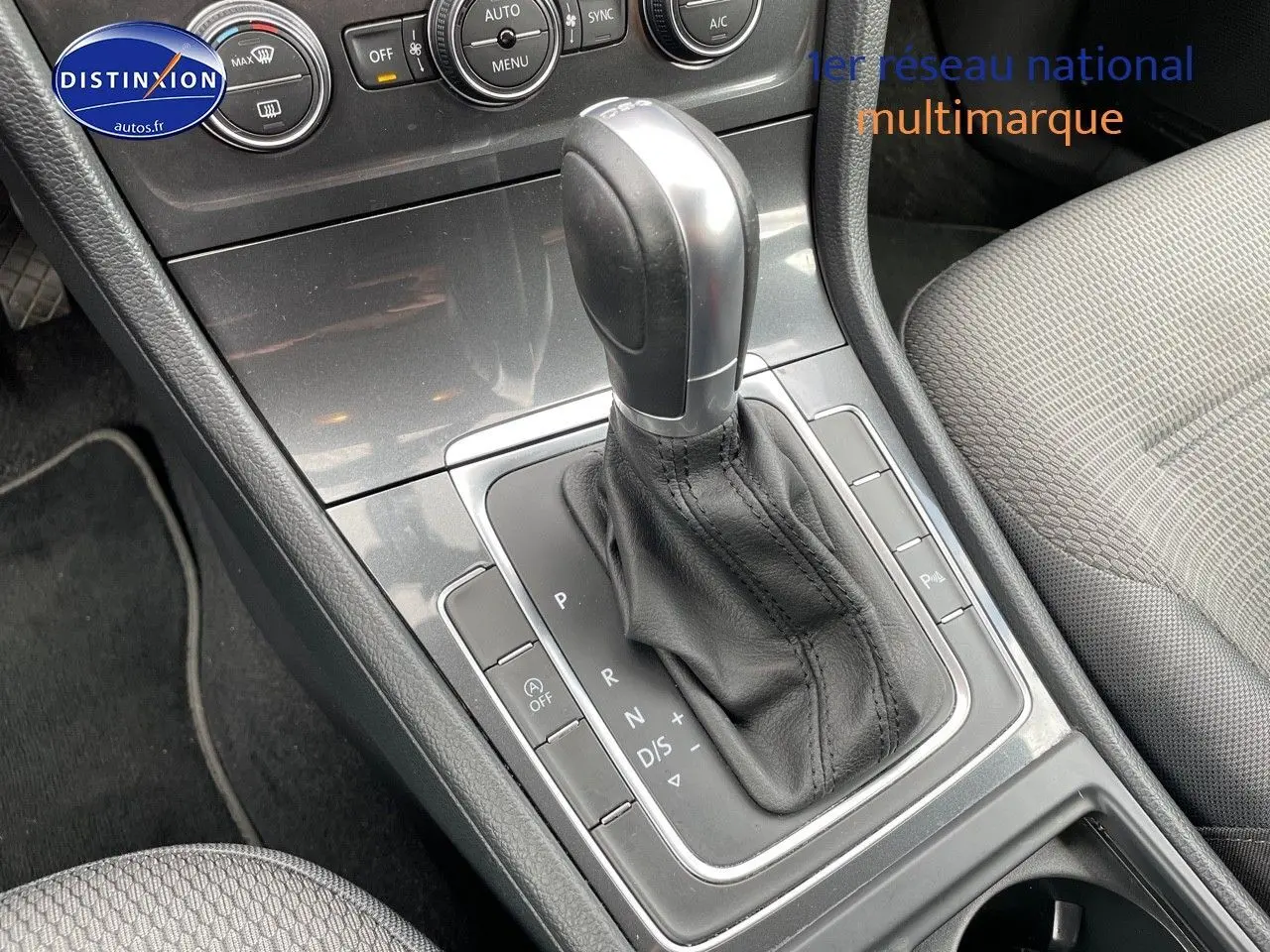 Gros plan sur la console centrale de la Volkswagen Golf VII rouge, mettant en valeur le levier de vitesses automatique en cuir noir.