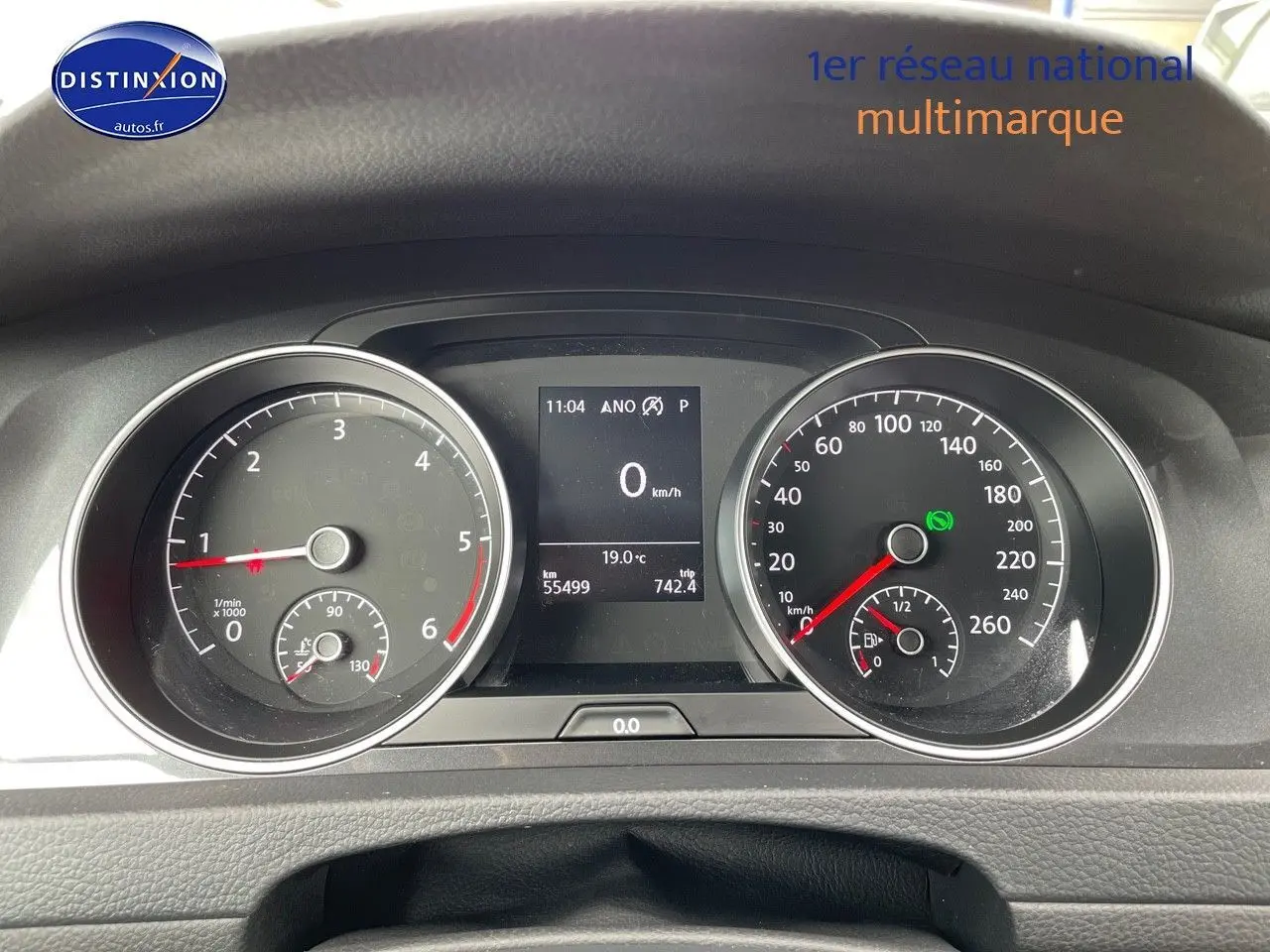 Vue rapprochée du tableau de bord de la Volkswagen Golf VII rouge, affichant le compteur et l'ordinateur de bord.