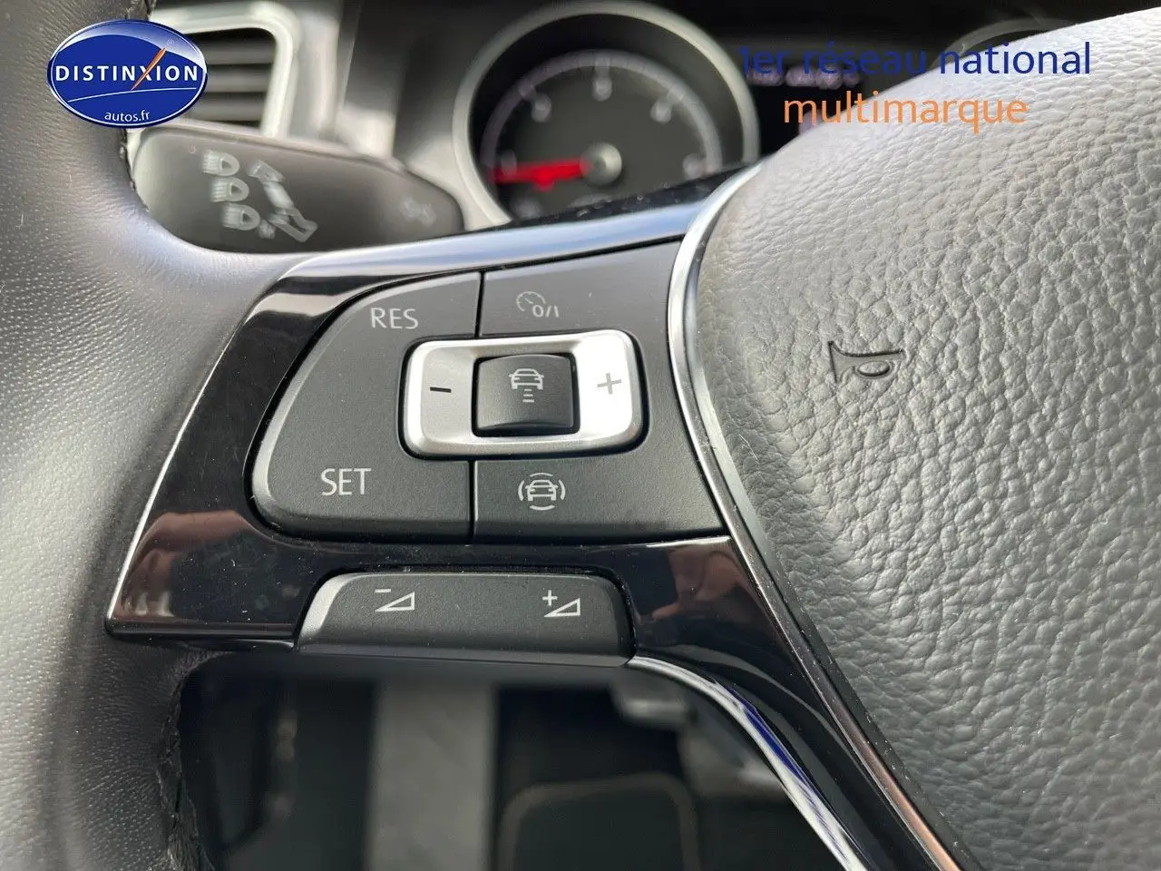 Gros plan sur le volant noir de la Volkswagen Golf VII avec commandes de régulateur de vitesse visibles.