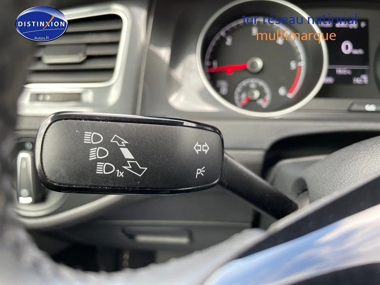 Gros plan sur la manette de clignotant à gauche du volant dans l’habitacle d’une Volkswagen Golf rouge de 2018.