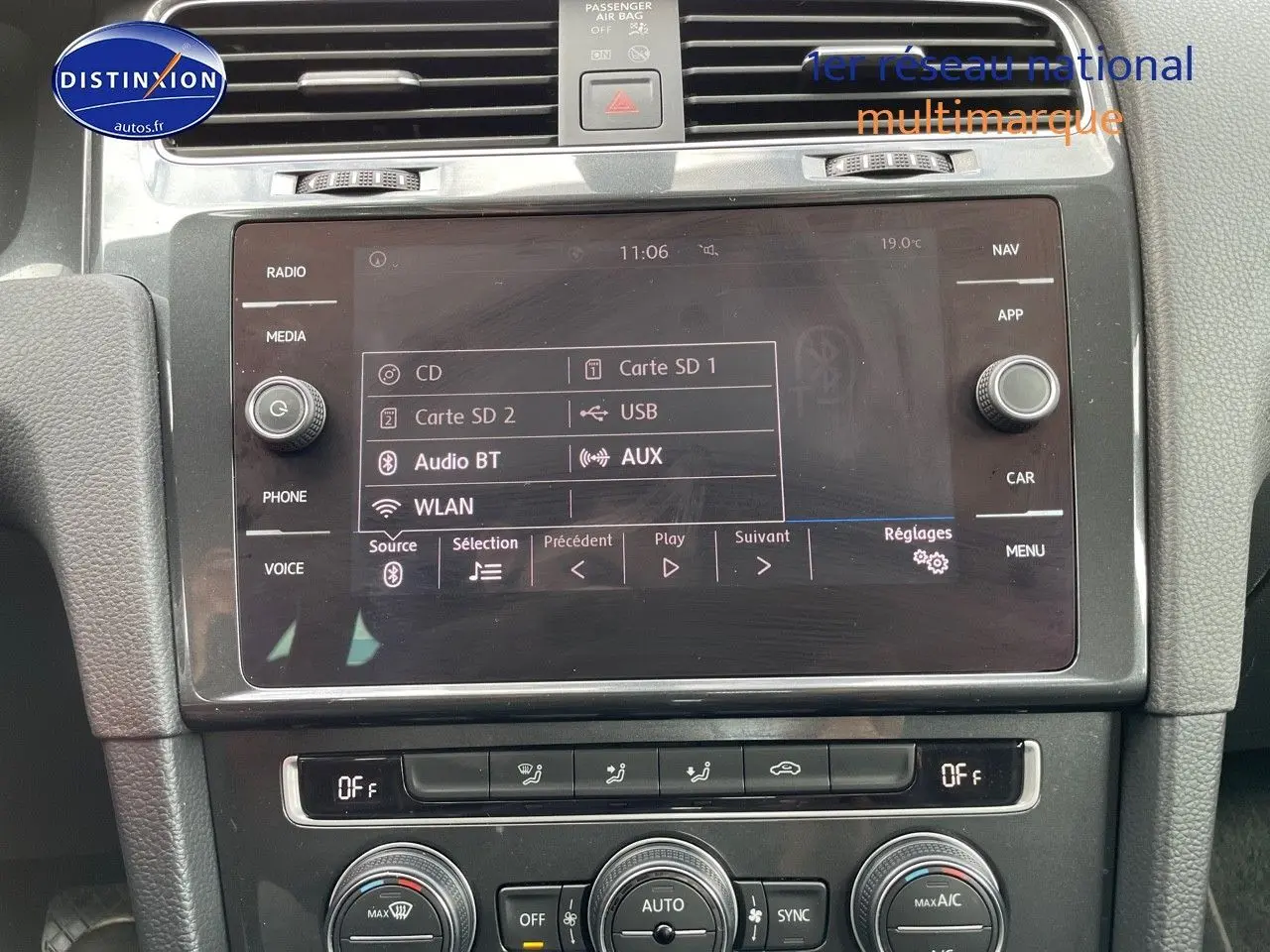 Vue rapprochée de l’écran multimédia et des commandes de climatisation d’une Volkswagen Golf VII rouge, intérieur noir.