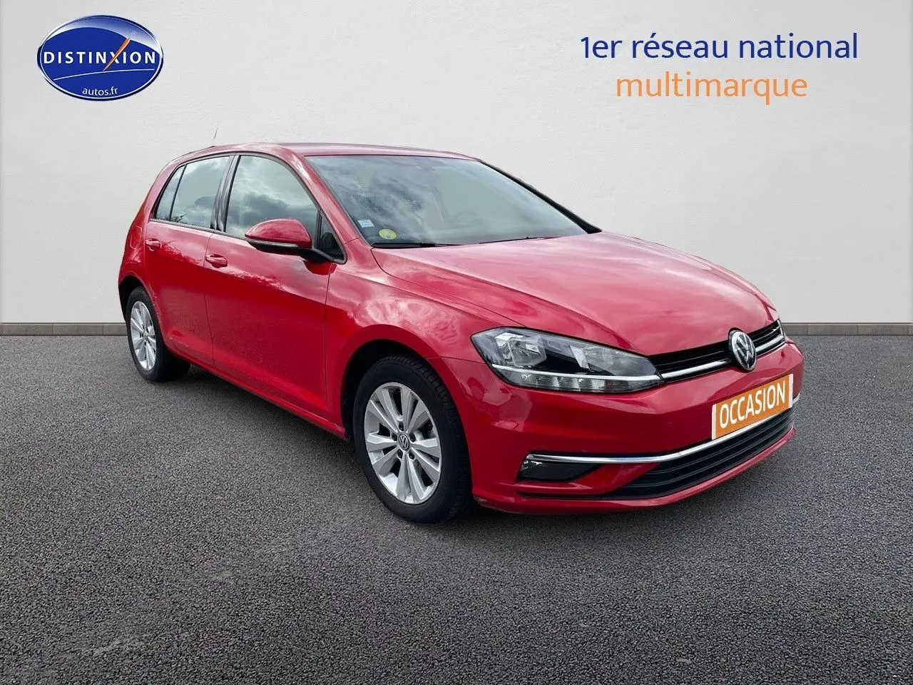 Volkswagen Golf VII rouge vue 3/4 avant droit sur sol gris avec plaque "OCCASION" orange.