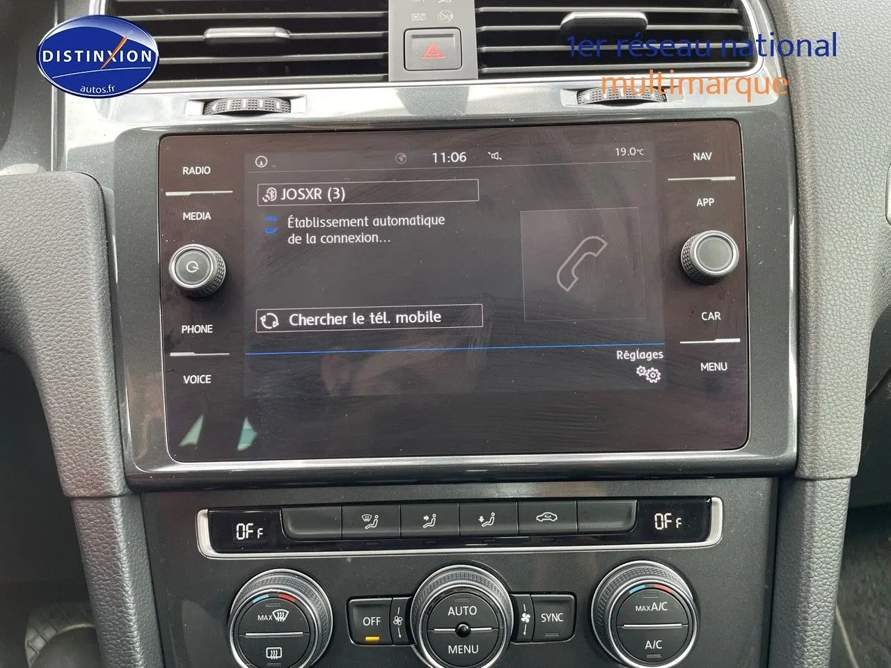 Vue rapprochée de la console centrale de la Volkswagen Golf VII rouge, affichant l’écran multimédia et les commandes de climatisation.