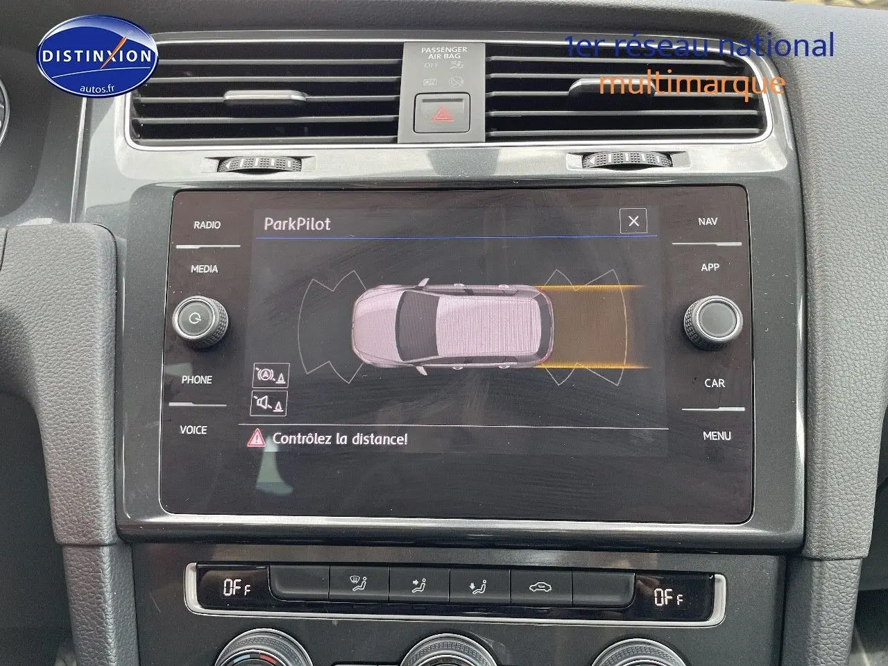 Vue rapprochée de l’écran central tactile du tableau de bord d’une Volkswagen Golf rouge, affichant le système ParkPilot.