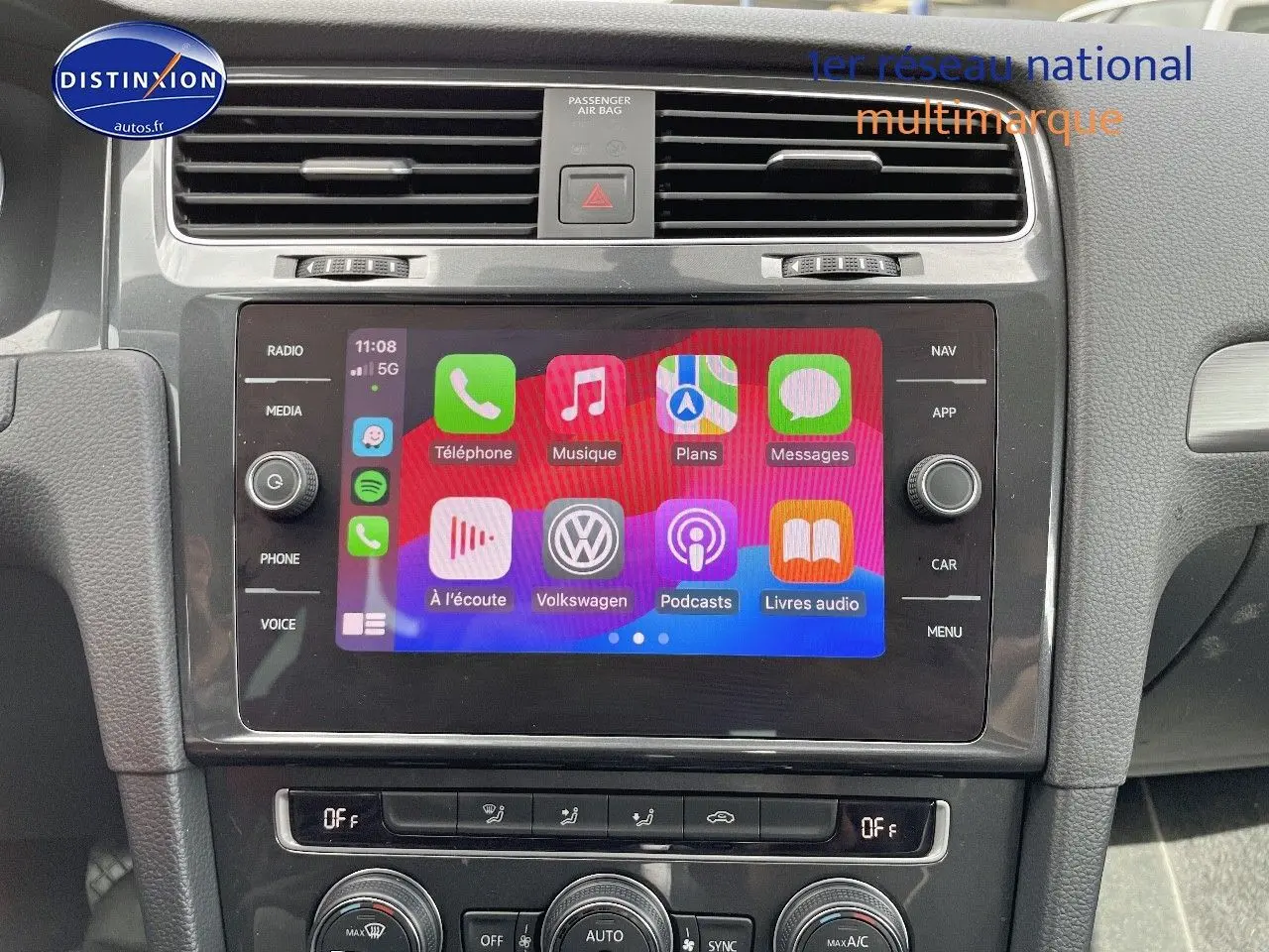 Vue rapprochée de l’écran tactile central du tableau de bord d’une Volkswagen Golf rouge de 2018, affichant l’interface multimédia.