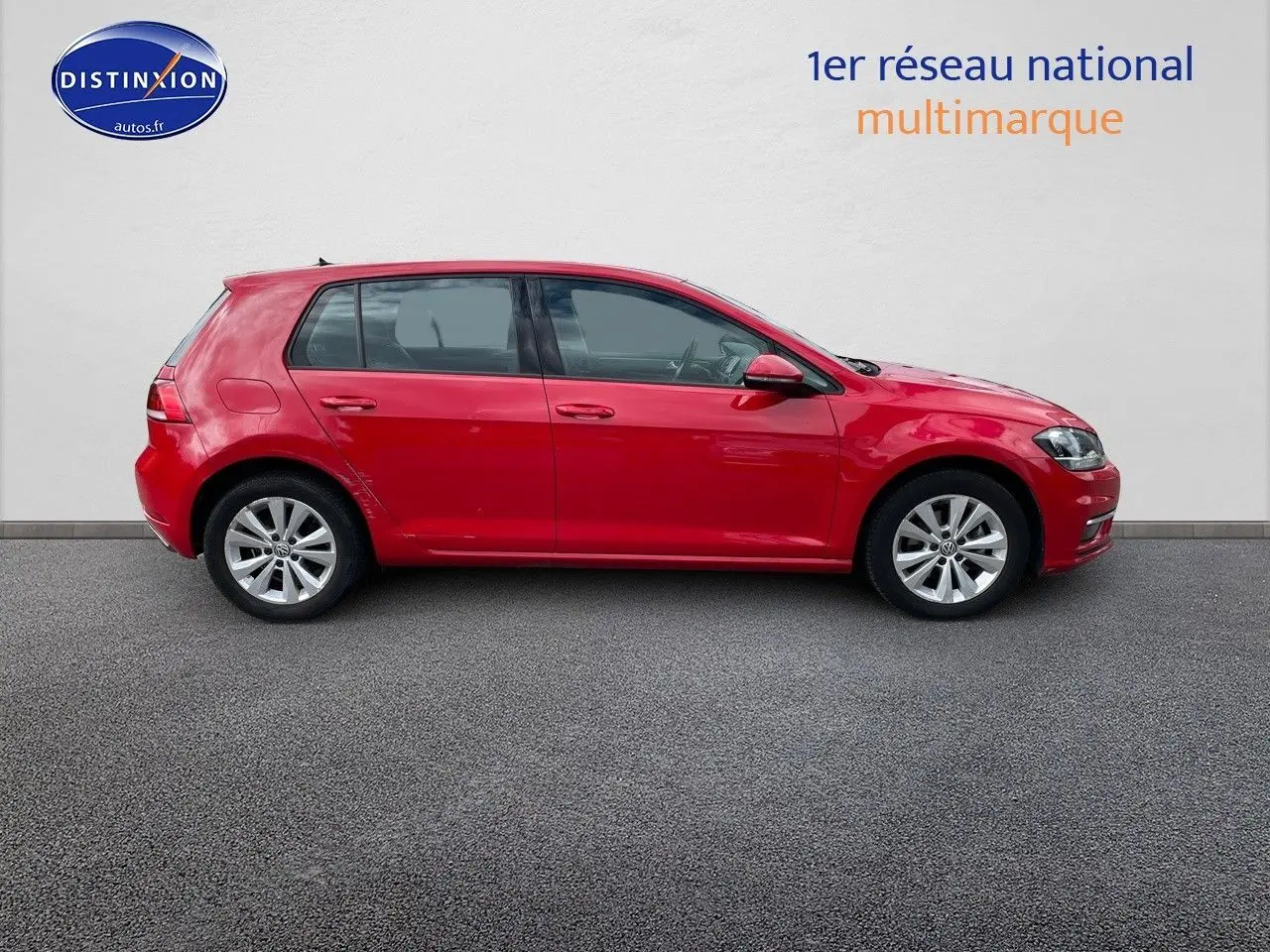 Profil droit d'une Volkswagen Golf VII rouge de 2018, avec jantes alliage et vitres légèrement teintées.