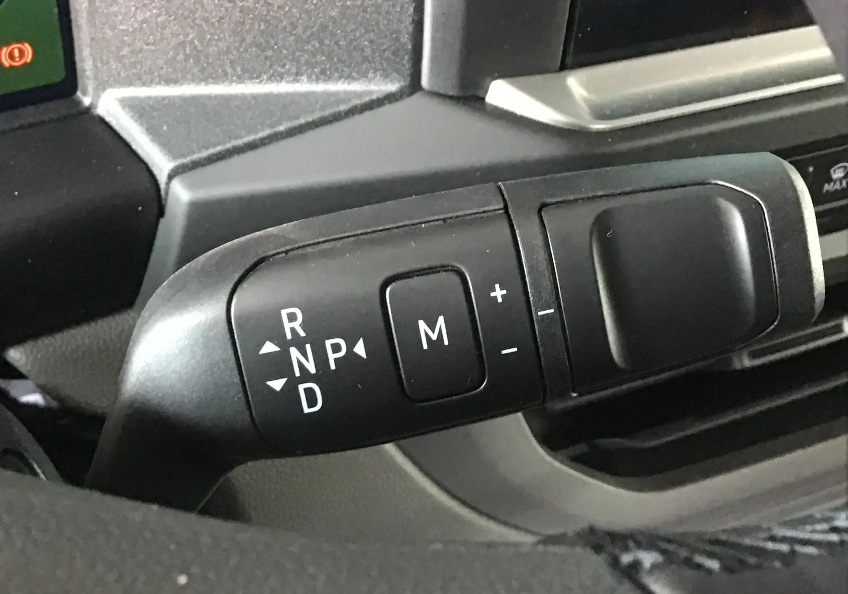 Le levier de boîte automatique avec commandes de mode manuel dans l'habitacle du Volkswagen Transporter gris anthracite.