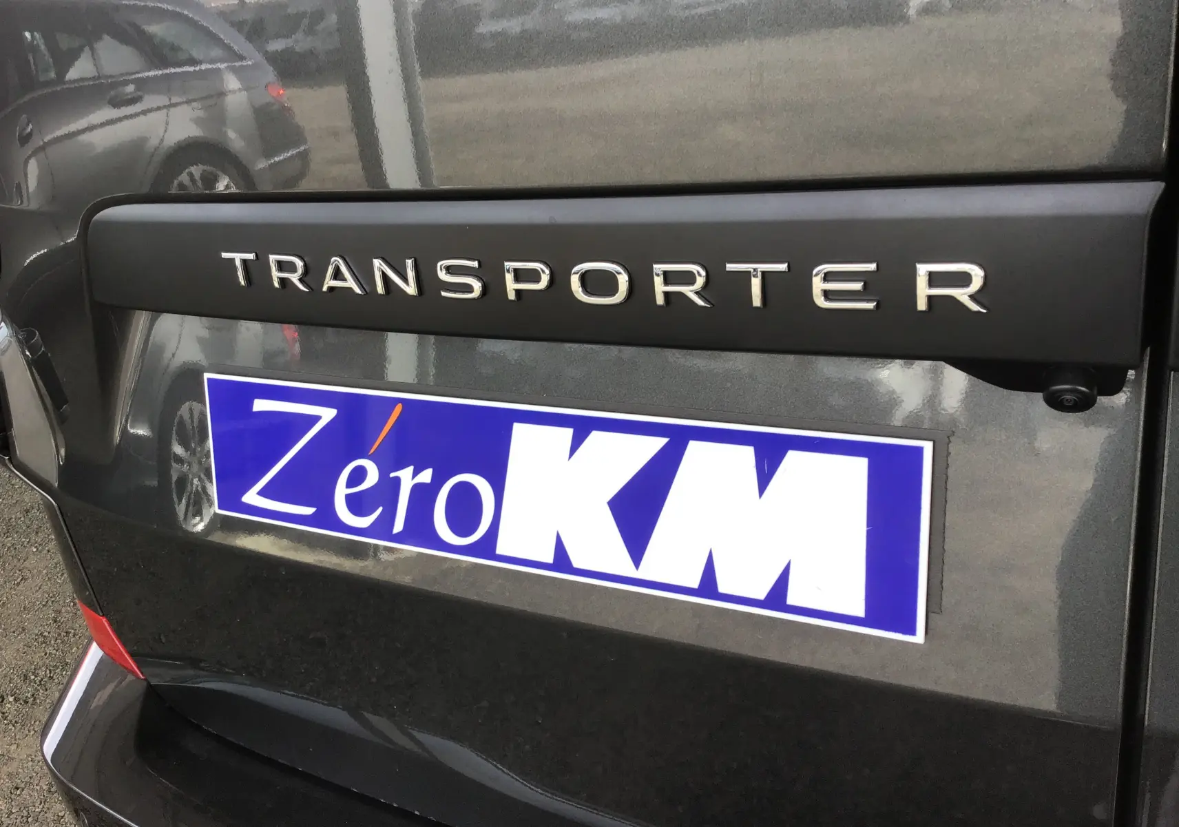 Gros plan sur l'arrière gris anthracite du Volkswagen Transporter avec logo et plaque Zéro KM visible.