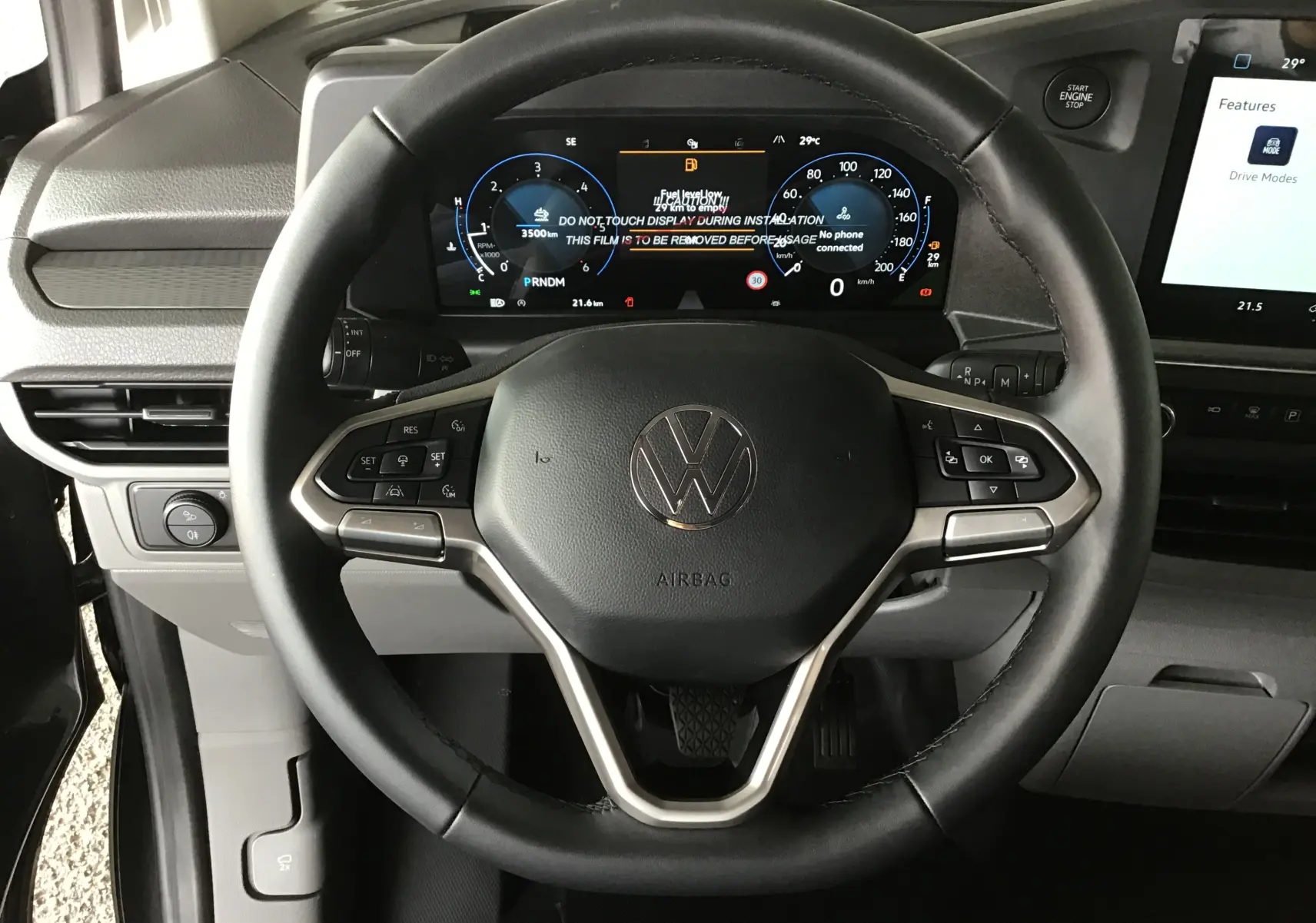 Vue rapprochée du volant multifonctions et du tableau de bord numérique du Volkswagen Transporter T7 gris anthracite, intérieur moderne.