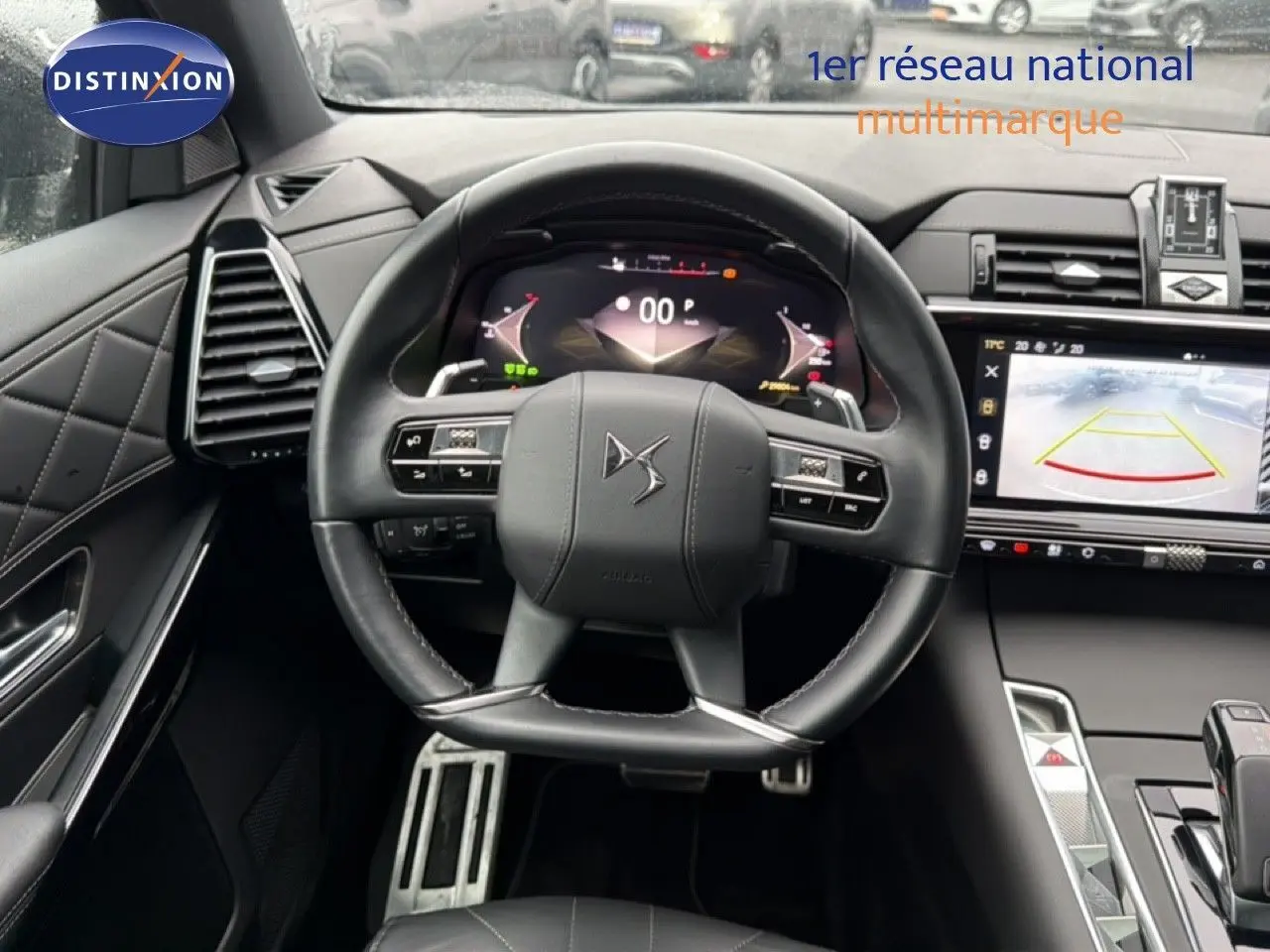 Vue intérieure centrée sur le volant cuir noir du DS7 2024 avec tableau de bord numérique et écran de recul.