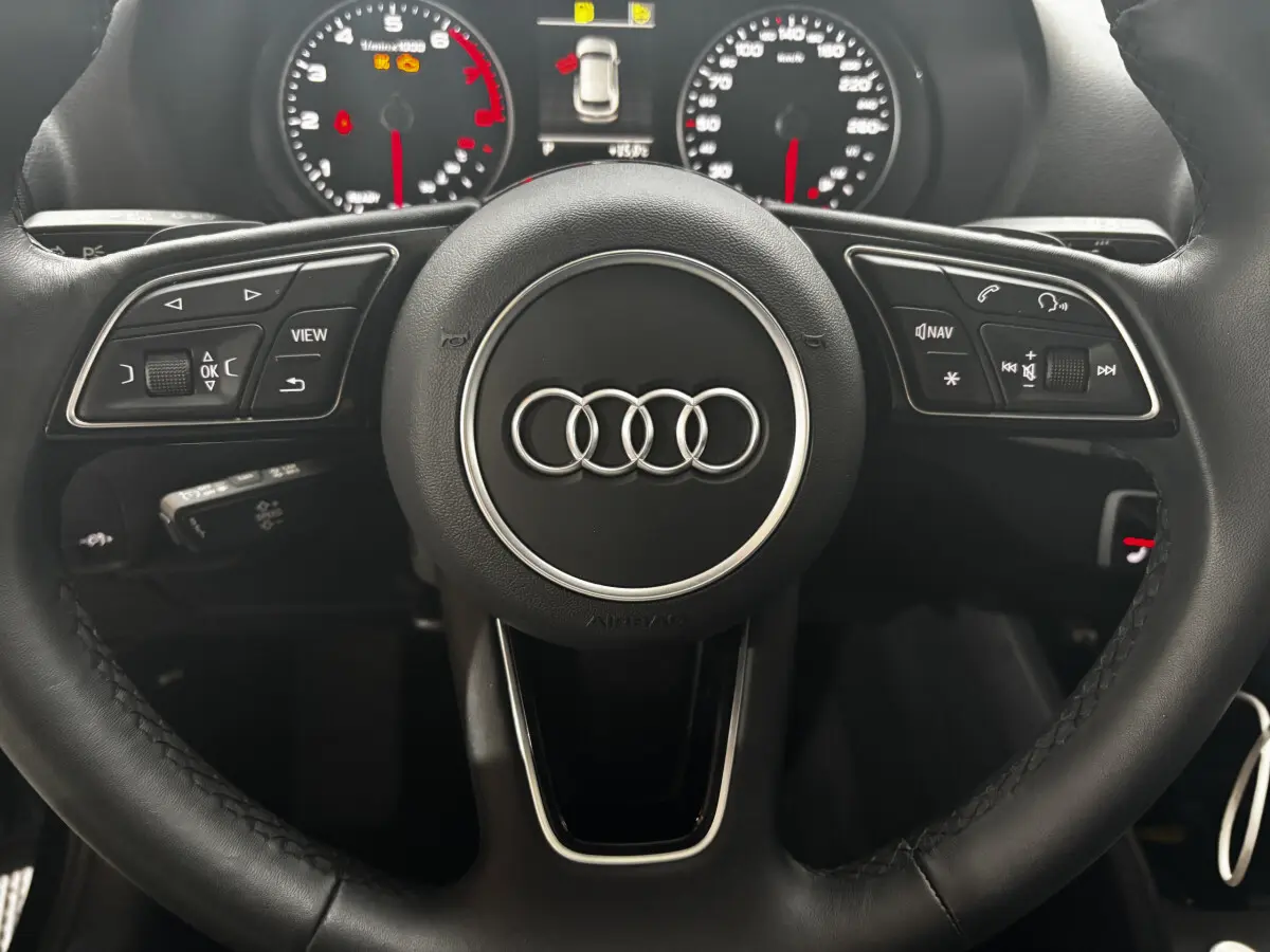 Vue rapprochée du volant cuir noir multifonctions d’un Audi Q2 35 TFSI 150 S Tronic S Line avec combiné d’instruments digital.
