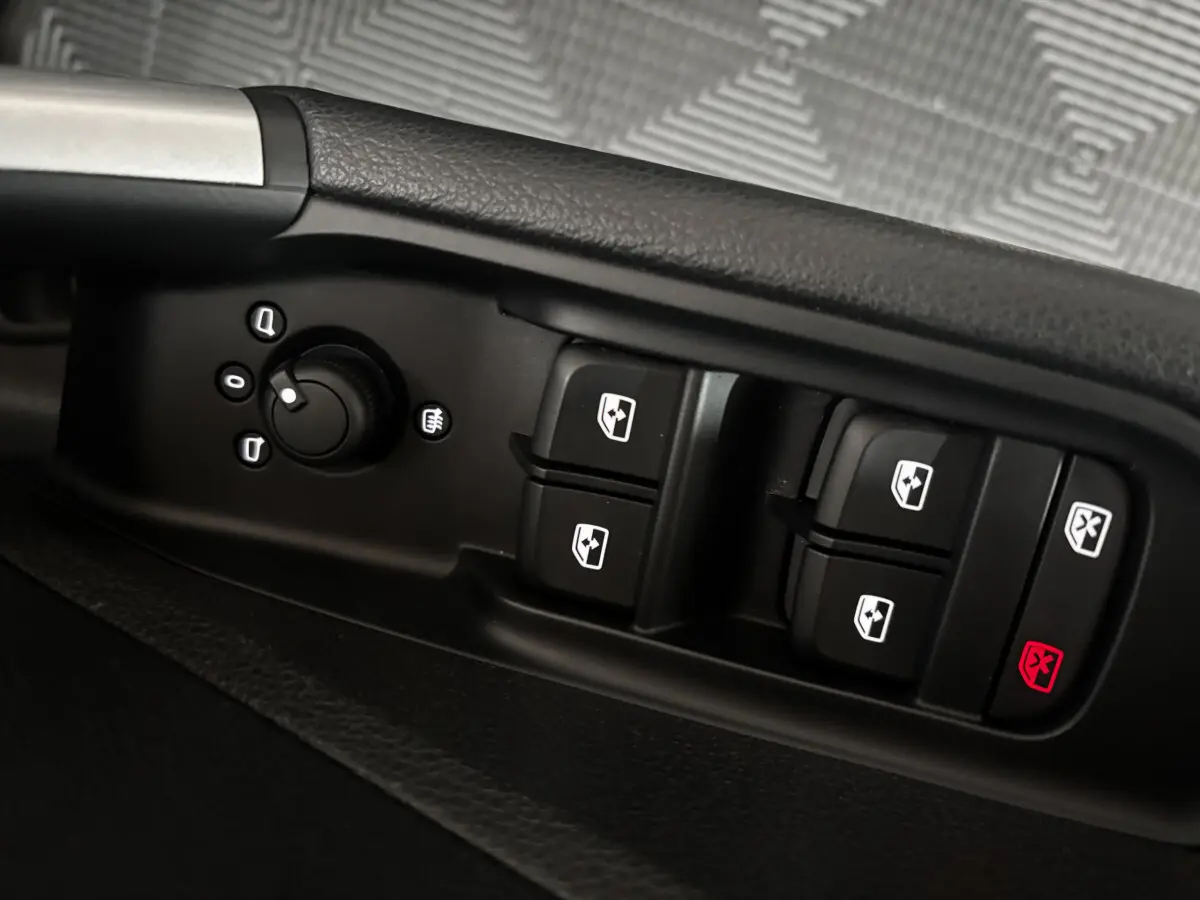 Gros plan sur les commandes de lève-vitres et réglage des rétroviseurs côté conducteur d’un Audi Q2 noir 2023.