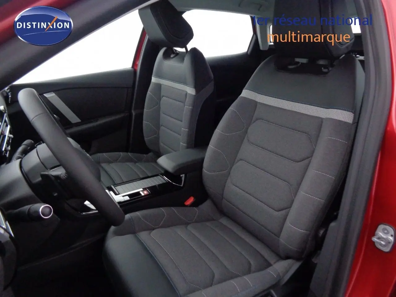 Vue intérieure côté conducteur de la Citroën C4 rouge Elixir Metal, sièges tissu gris et volant multifonction.