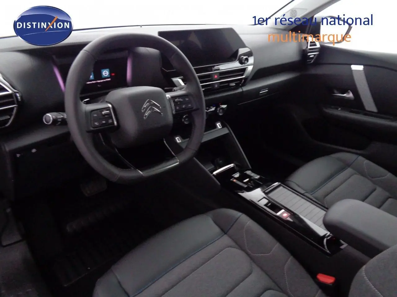 Vue intérieure côté conducteur de la Citroën C4 2023, tableau de bord noir avec volant multifonction et sièges tissu noir.
