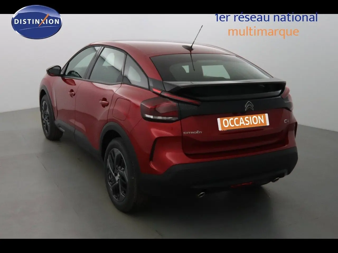 Vue 3/4 arrière droite d'une Citroën C4 rouge Elixir métal avec toit noir et jantes noires en studio.