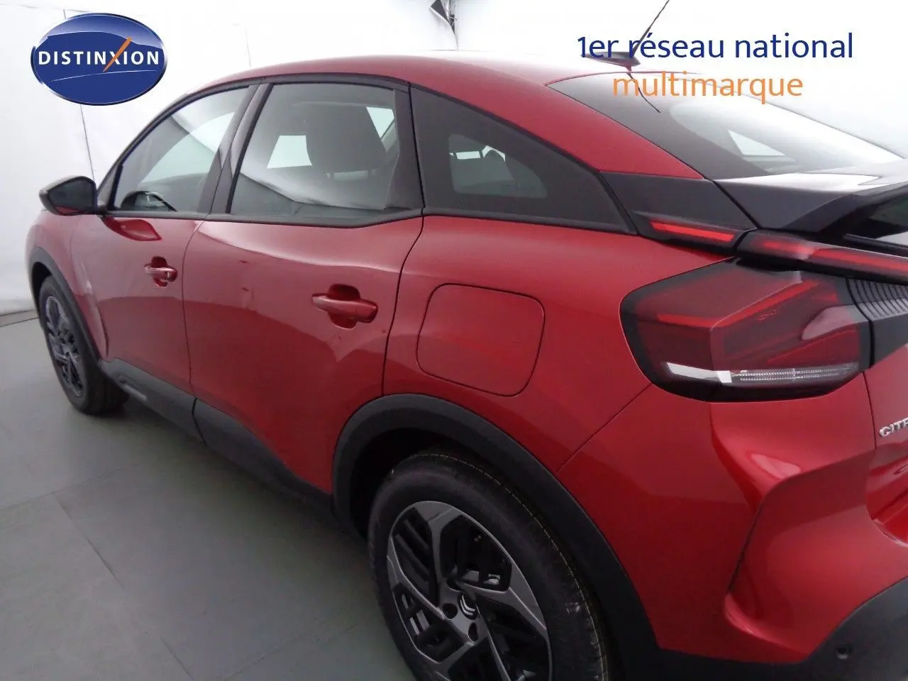 Vue 3/4 arrière gauche d'une Citroën C4 rouge Elixir métal avec toit noir et jantes alliage bicolores.