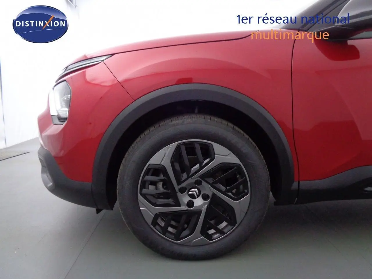 Gros plan sur la roue avant gauche d'une Citroën C4 rouge Elixir Métal avec jante alliage noire et grise.