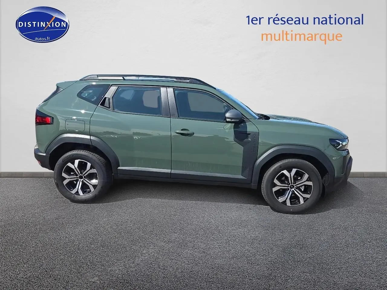 Vue de profil côté gauche d'un Dacia Duster vert kaki 2025 avec jantes alu et barres de toit noires.