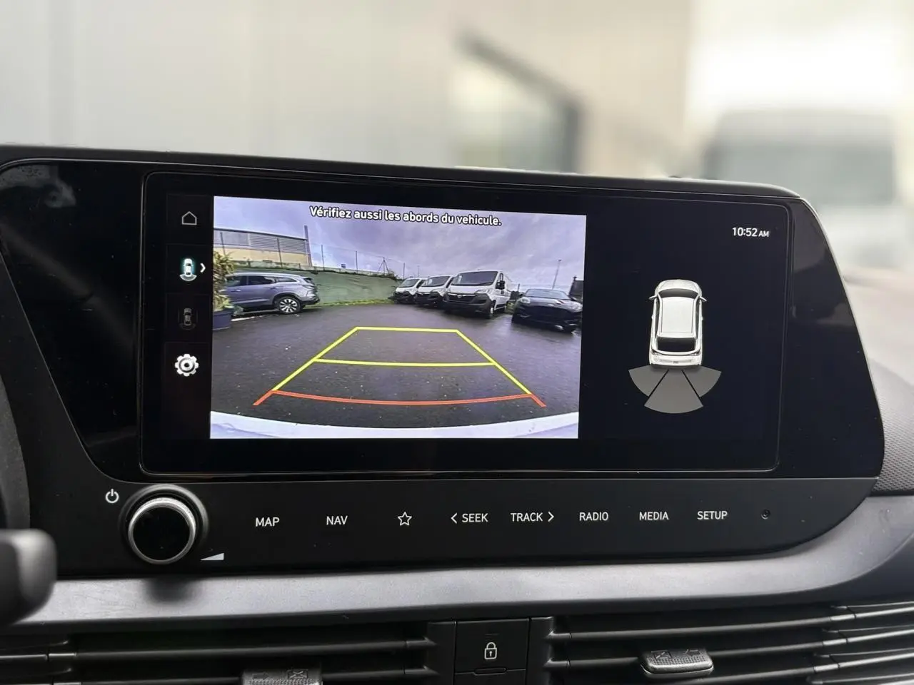Écran tactile intérieur montrant la caméra de recul et l’aide au stationnement du Hyundai i20 blanc Atlas.