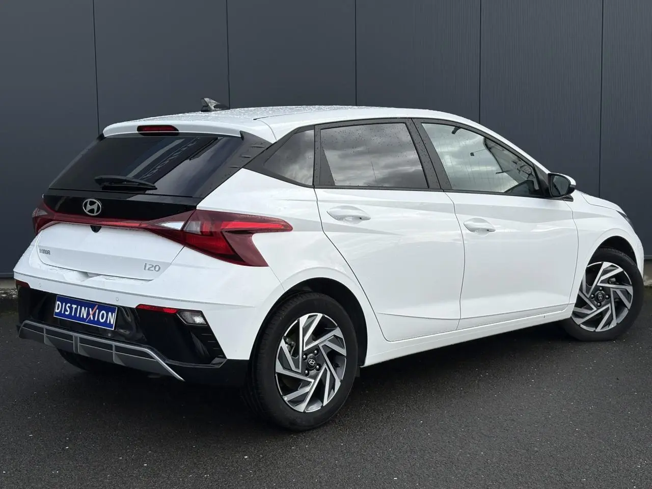 Vue 3/4 arrière droite d'une Hyundai i20 blanche Atlas avec jantes alliage et vitres arrière surteintées.