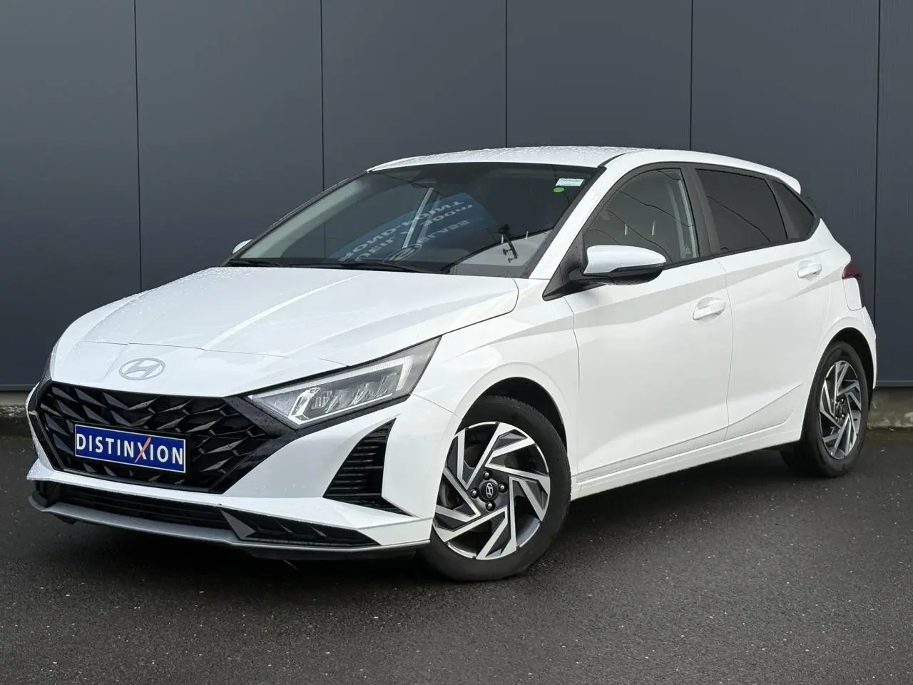 Hyundai i20 blanc Atlas vue 3/4 avant droit, avec calandre noire et jantes alliage 16 pouces diamantées.