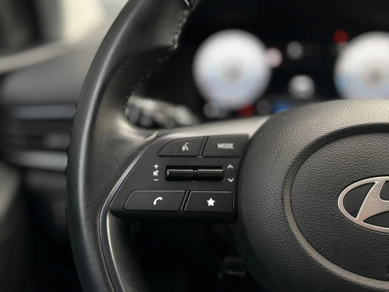 Gros plan sur le volant cuir de la Hyundai i20 2025 avec commandes multimédia intégrées côté gauche.