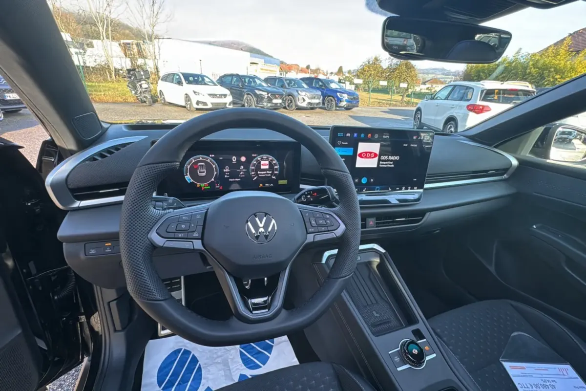 Vue intérieure centrée sur le volant cuir multifonctions du Volkswagen T-Roc noir ebène avec tableau de bord digital.