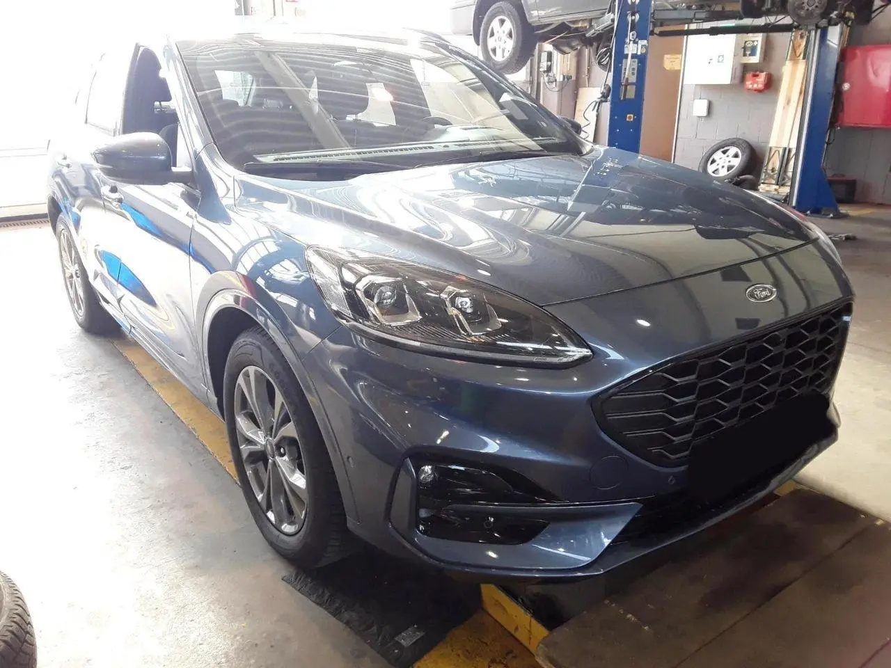 Vue 3/4 avant droit d'un Ford Kuga 2024 bleu azur avec calandre noire et jantes alliage 18 pouces.