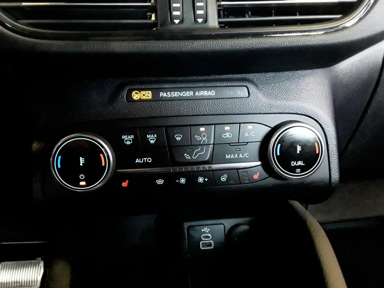 Vue rapprochée de la console centrale noire du Ford Kuga 2024, montrant les commandes de climatisation et sièges chauffants.