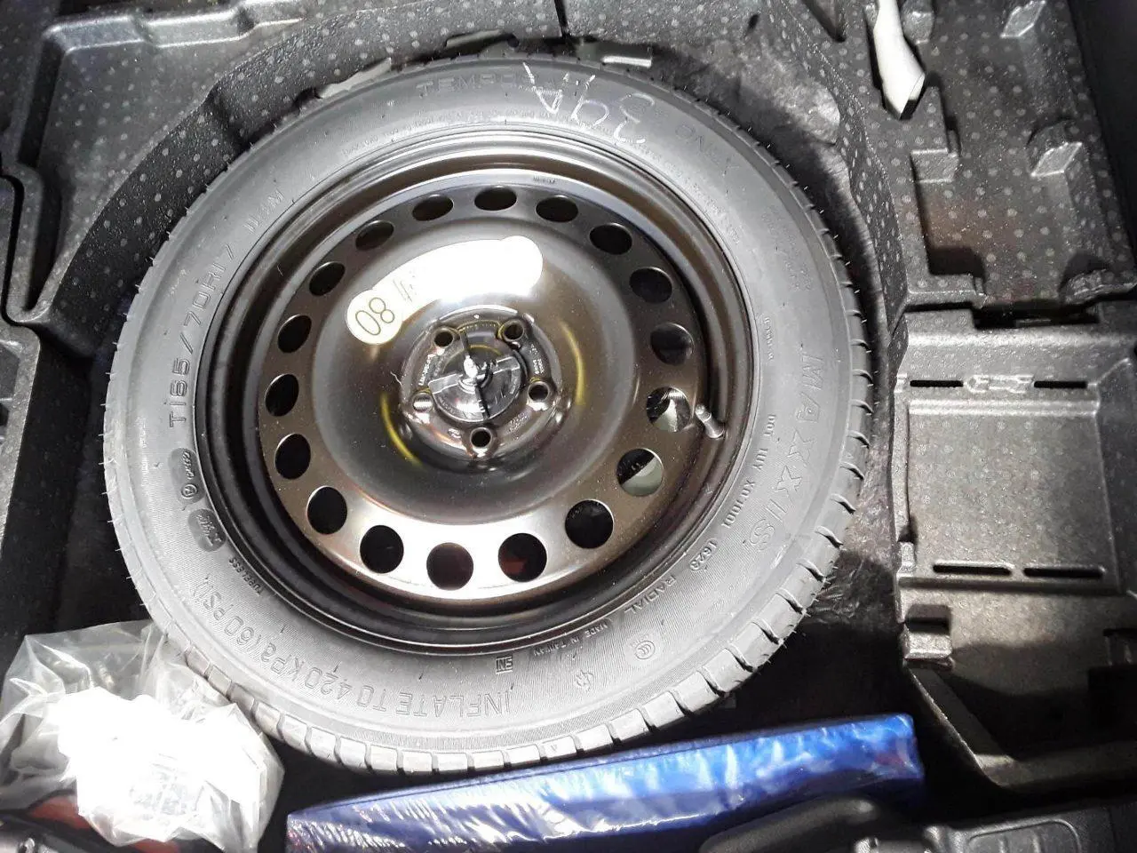 Gros plan sur la roue de secours galette noire dans le coffre du Ford Kuga 2024 Bleu Azur.