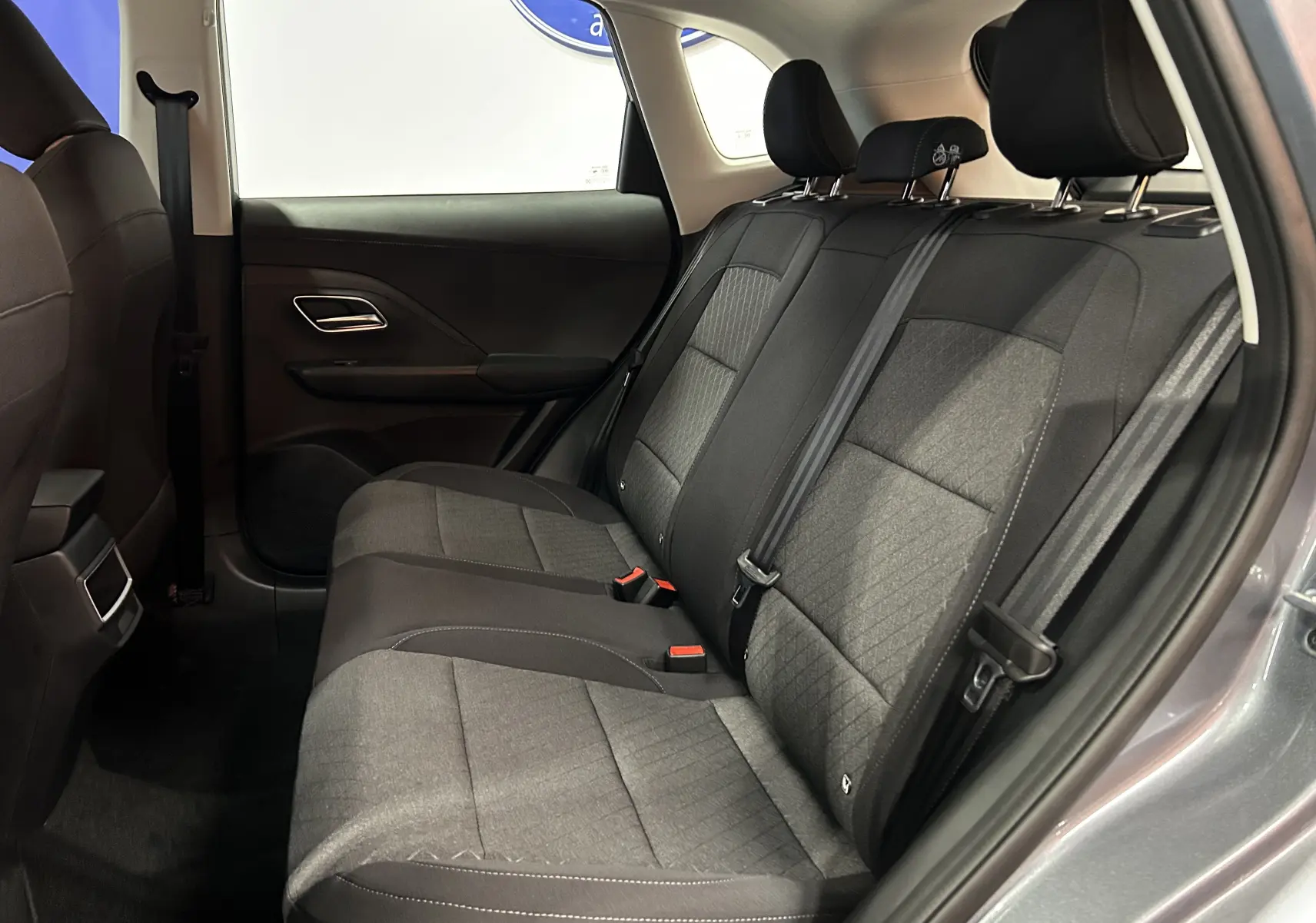 Vue latérale droite de l'habitacle arrière du MG ZS Hybrid+ 2025 avec sièges tissu gris et ceinture de sécurité noire.