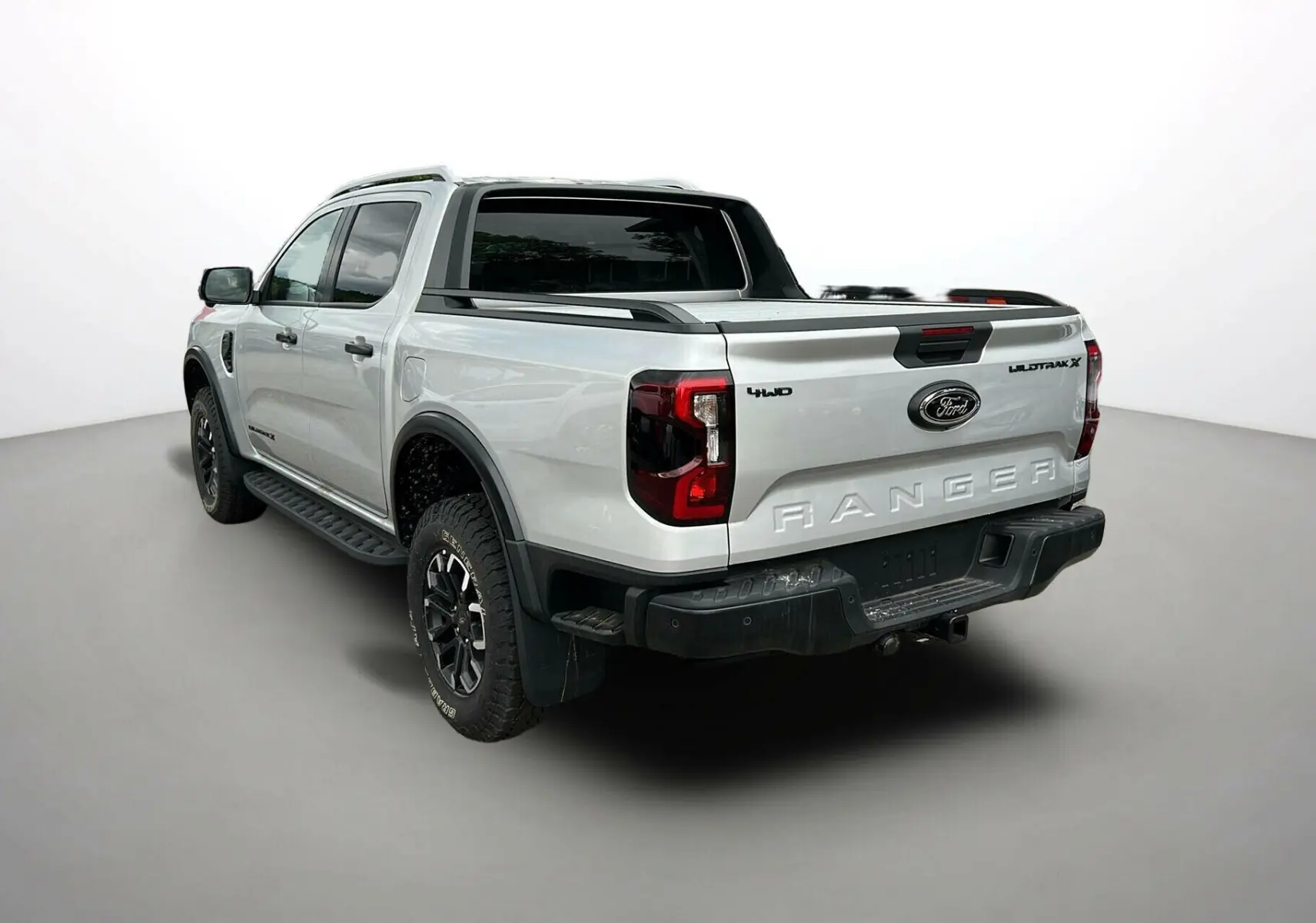 Ford Ranger 2025 gris iconic en 3/4 arrière droit, avec arceau sport, jantes noires et benne ouverte.