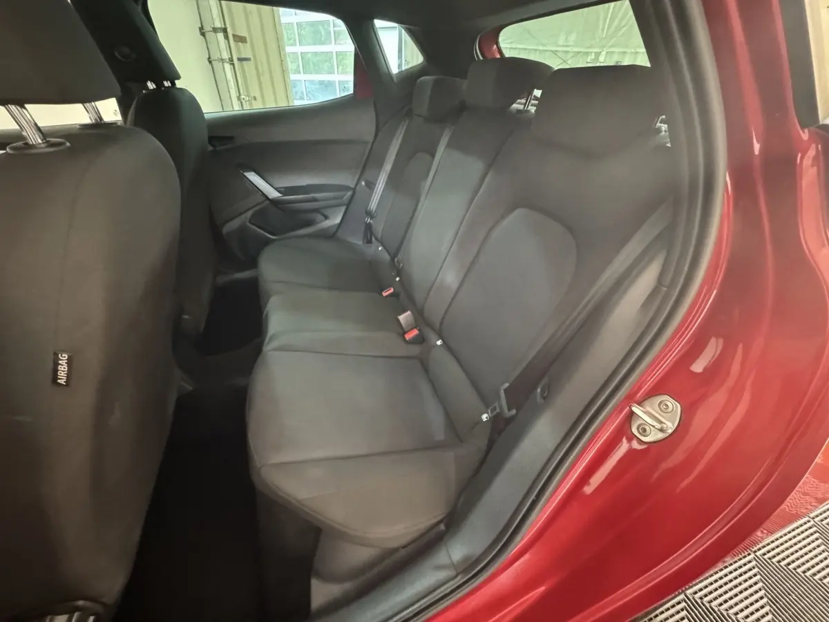 Vue intérieure côté droit sur la banquette arrière noire d’une SEAT Ibiza rouge 2024 avec portière ouverte.