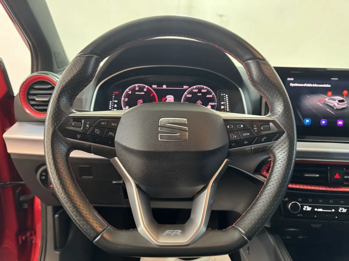 Vue rapprochée du volant cuir perforé avec logo FR et tableau de bord numérique d'une SEAT Ibiza rouge 2024.