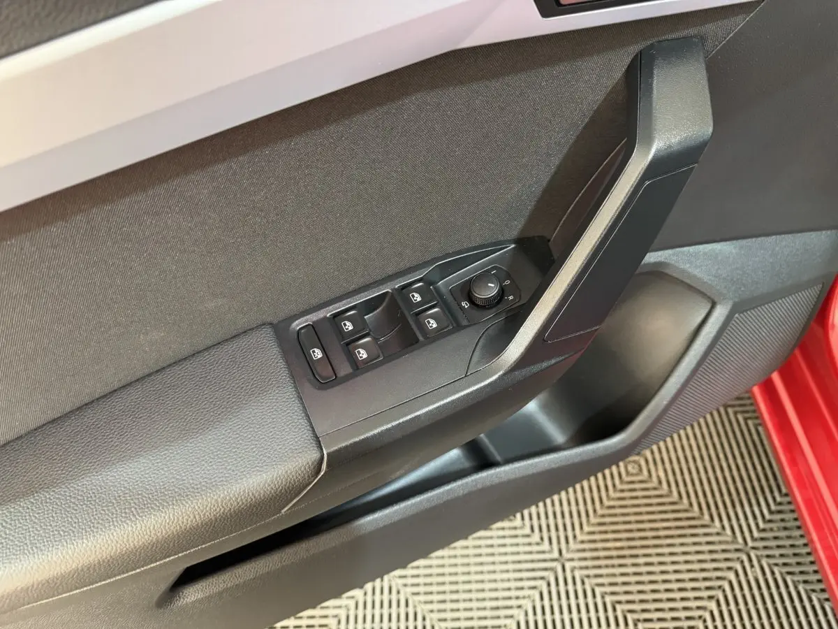 Gros plan sur la porte côté conducteur rouge de la SEAT IBIZA 2024, montrant les commandes électriques des vitres et rétroviseurs.