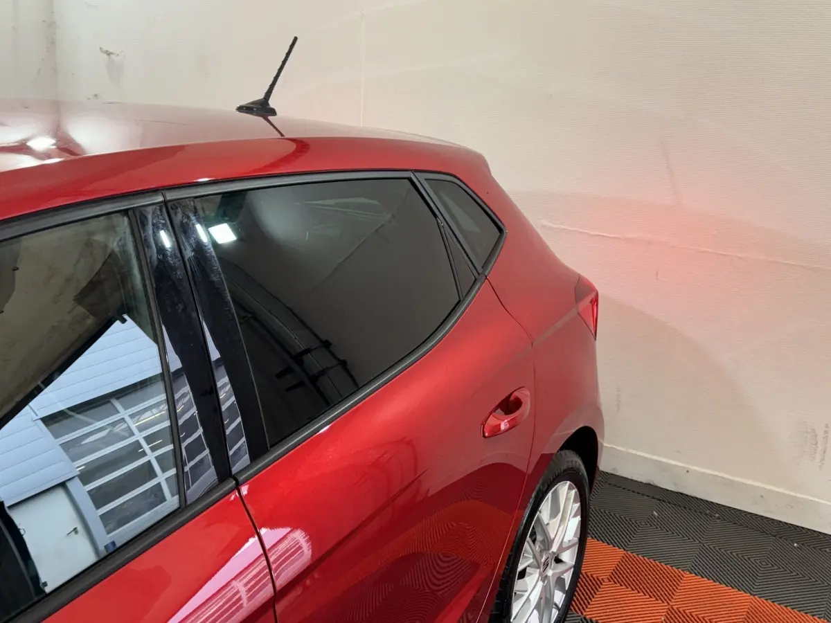 Vue 3/4 arrière droite d'une SEAT Ibiza 2024 rouge avec vitres teintées et jantes alliage argentées.